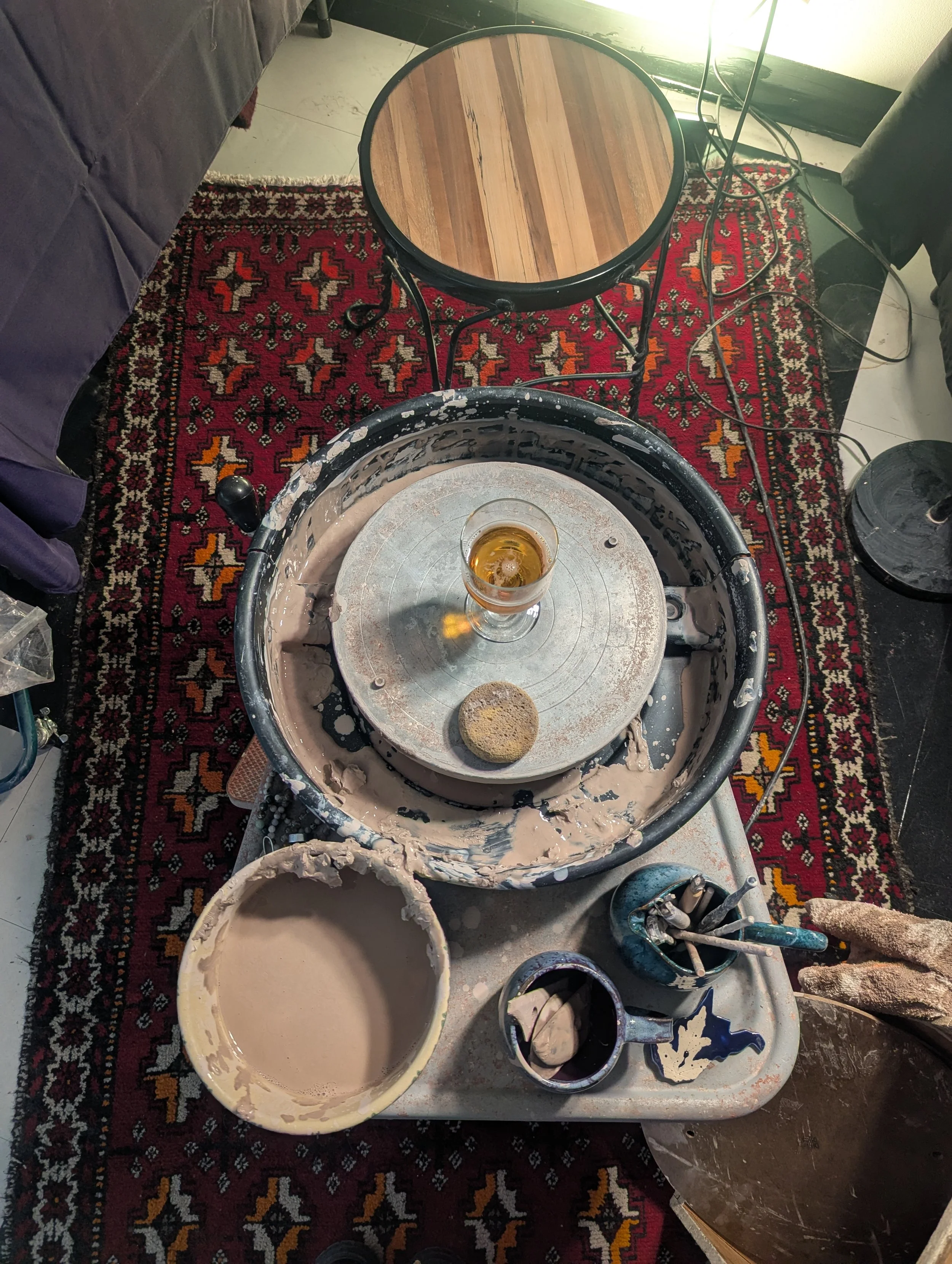 picture of meghann's live demo set-up including her pottery wheel and a glass of beer.