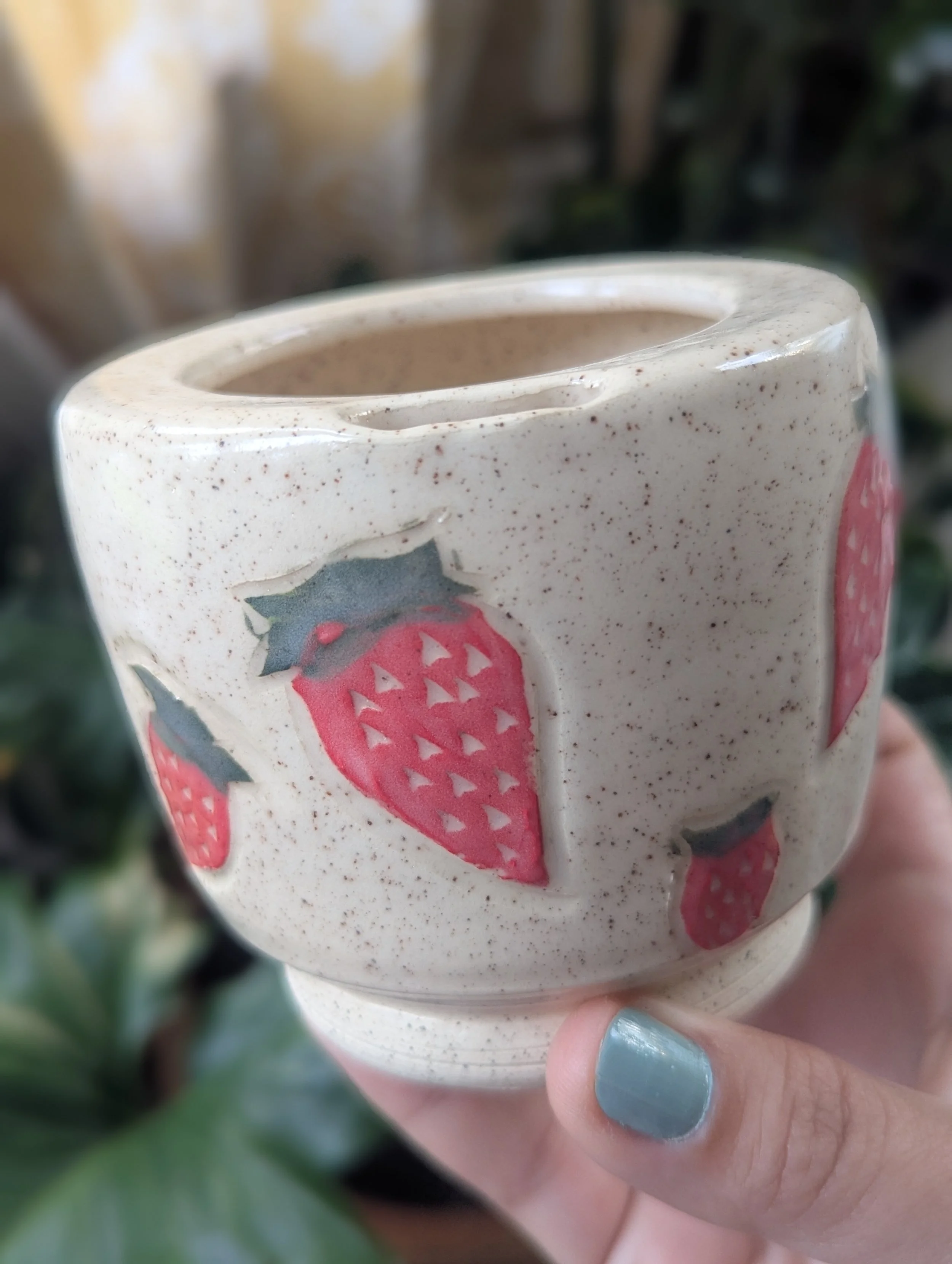 Matcha travel mug with strawberries carved on it.