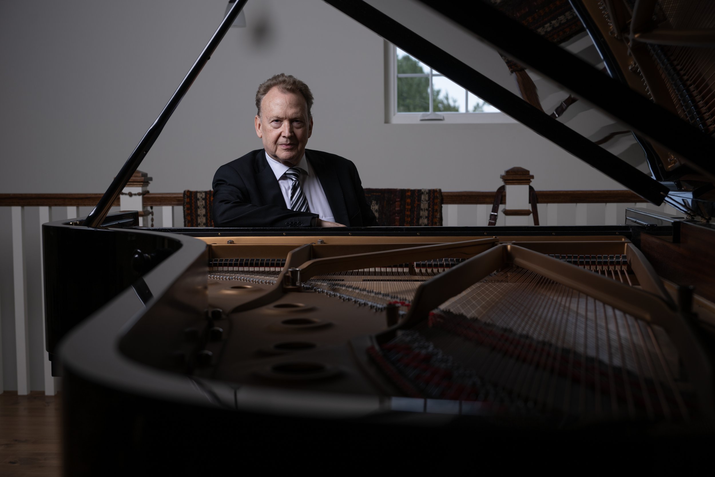 Peter Orth sitting at a grand Steinway piano looking into the camera.