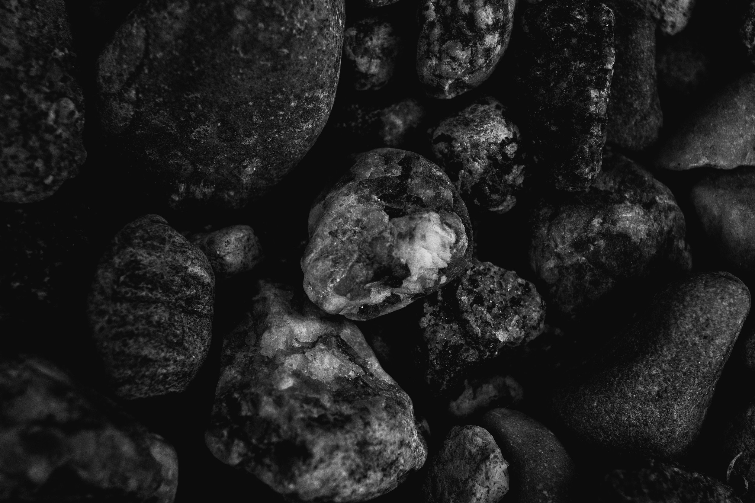 Schwarze und graue Kieselsteine in Nahaufnahme, verschiedene Größen und Formen.