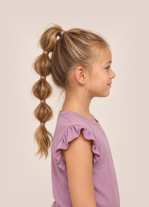 Side profile of a young girl with blonde hair styled in a long bubble ponytail.