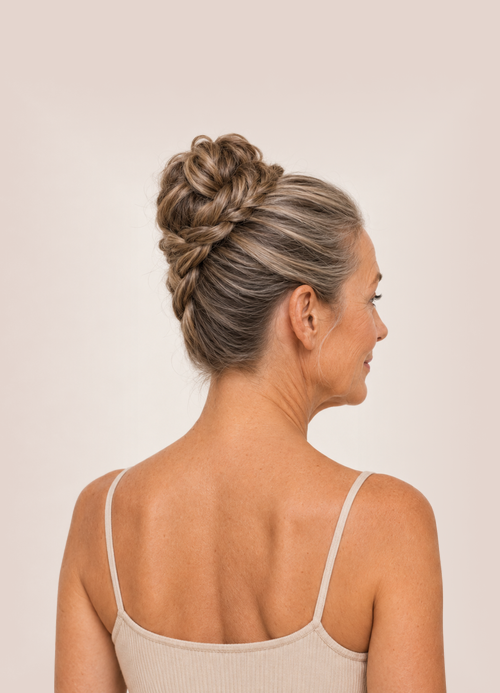 Rear side view of woman with grey hair styled in an intricately braided topknot.