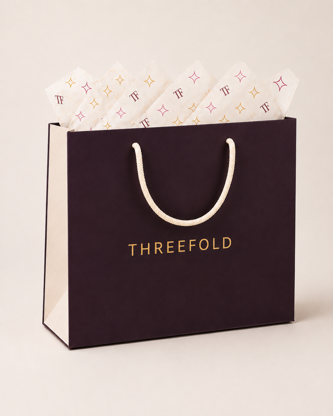 Aubergine Threefold gift bag with cream logo-printed tissue paper.