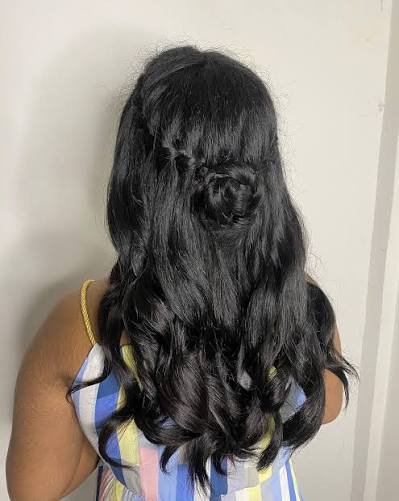 Side profile of a woman with long wavy hair and half cornrows.