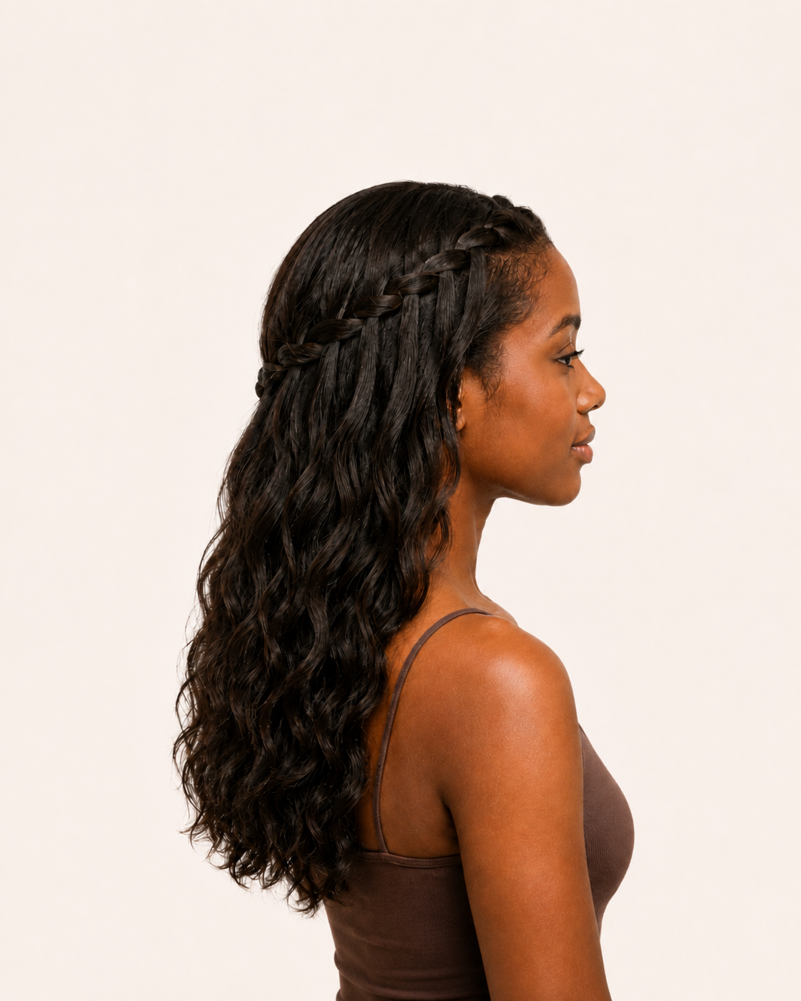 Side profile of a woman with long wavy hair and half cornrows.