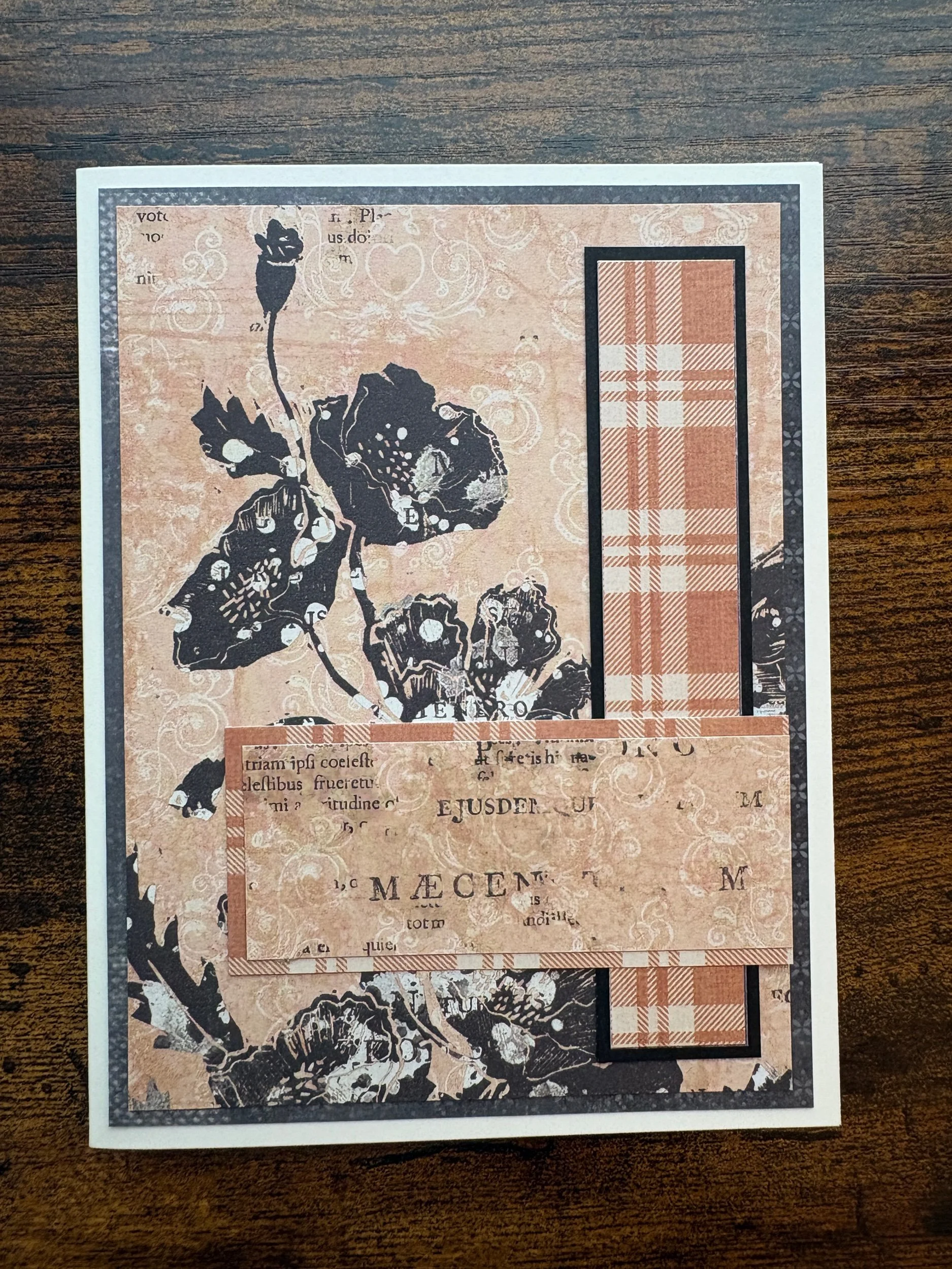 Close-up of a layered vintage-style collage with floral and text patterns, including a rectangle with a plaid pattern, on a wooden surface.