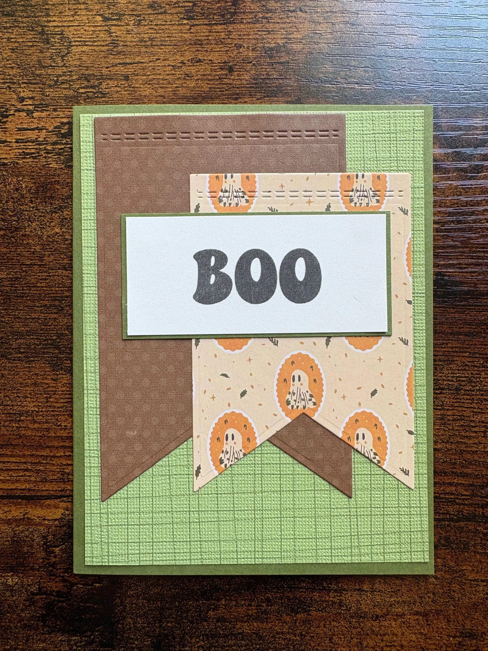 Crafted greeting card with layered paper, decorated with fall-themed patterns including pumpkins and leaves, and a handwritten "BOO" label.
