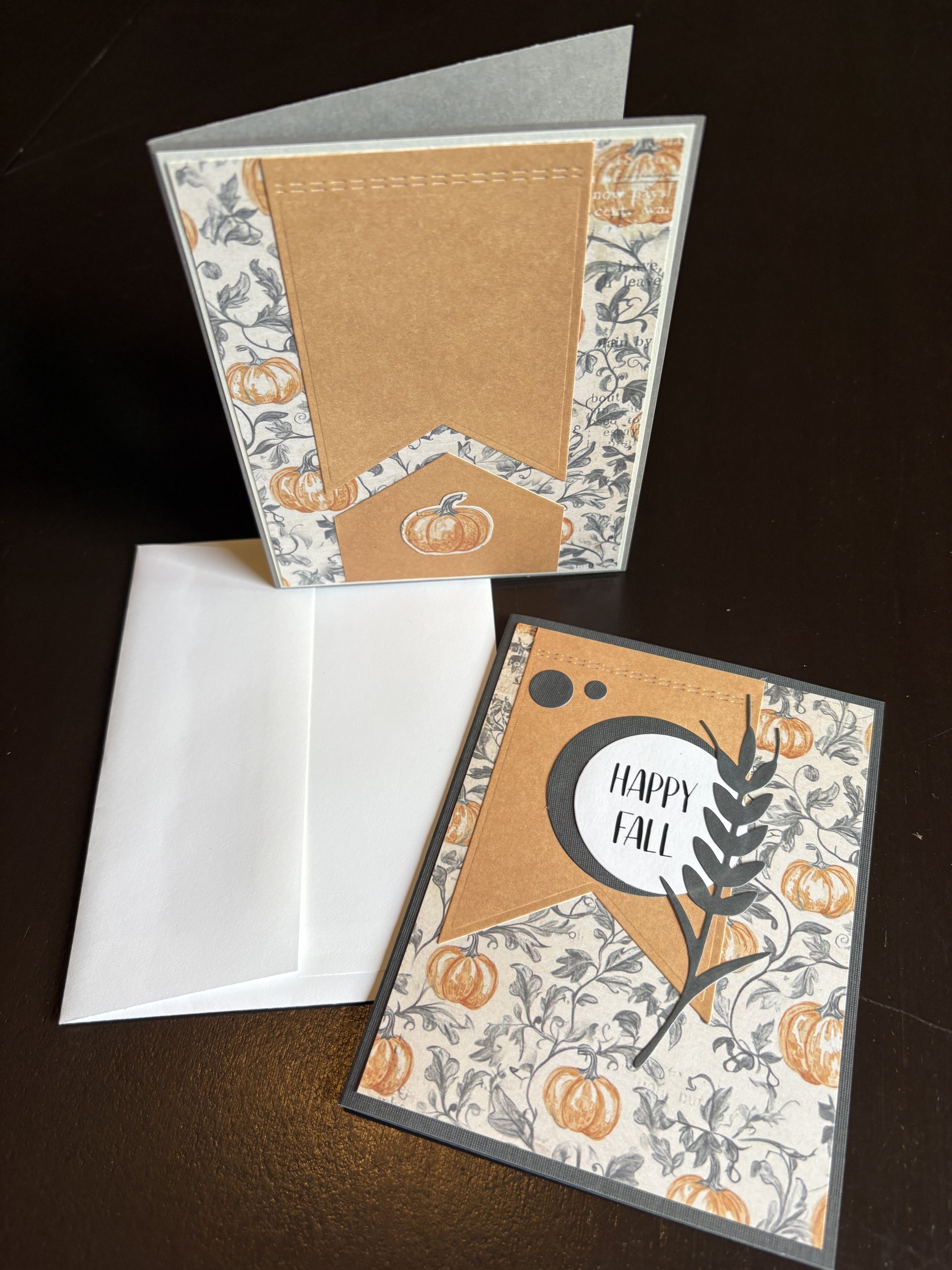 A greeting card with fall-themed pumpkin and leaf decoration, featuring a label that says 'HAPPY FALL' and a brown banner with a pumpkin illustration.