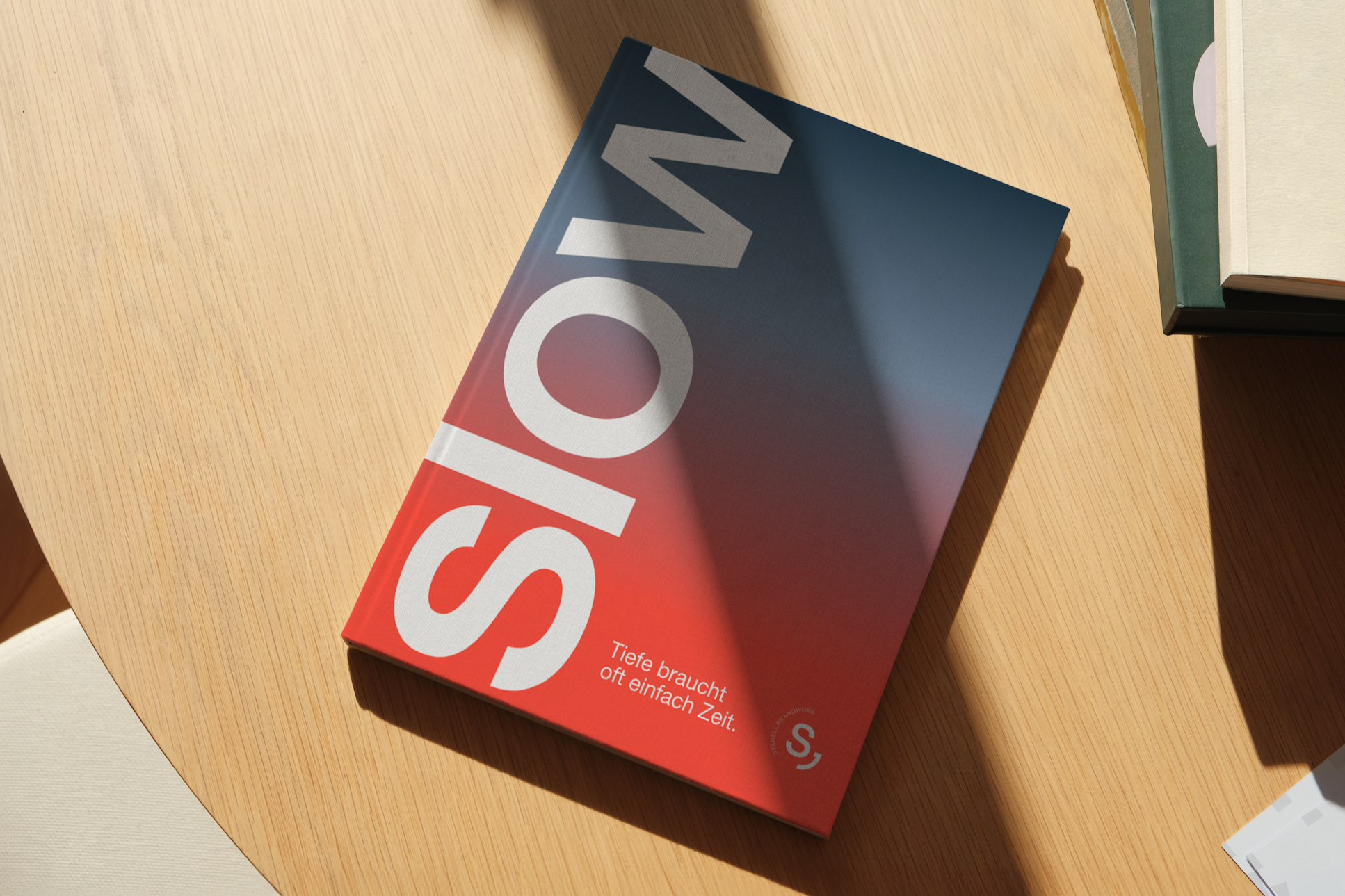 Ein Cover eines Buches mit Titel in großen Schriftzügen, das auf einem runden Holztisch liegt. Das Buch hat einen Farbverlauf von Rot zu Blau. Es trägt den Titel 'SOS' und darunter steht in kleinerer Schrift: 'Tiefe braucht oft einfach Zeit.'