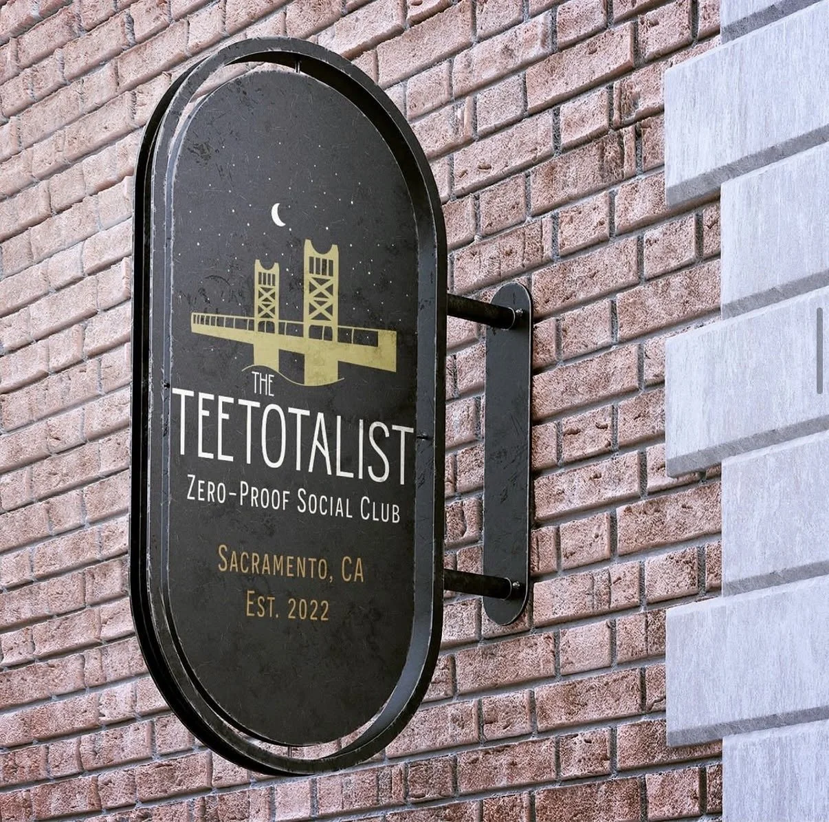 A sign mounted on a brick wall reads "The TETOTALIST Zero-Proof Social Club Sacramento, CA Est. 2022" with a graphic of a bridge and crescent moon.