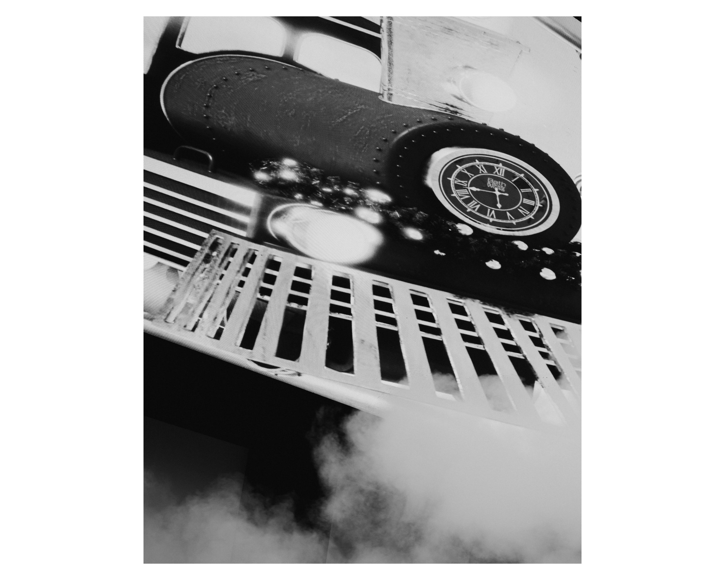 Black and white photo of a kitchen stove with a TV on top displaying a clock, viewed from a low angle.