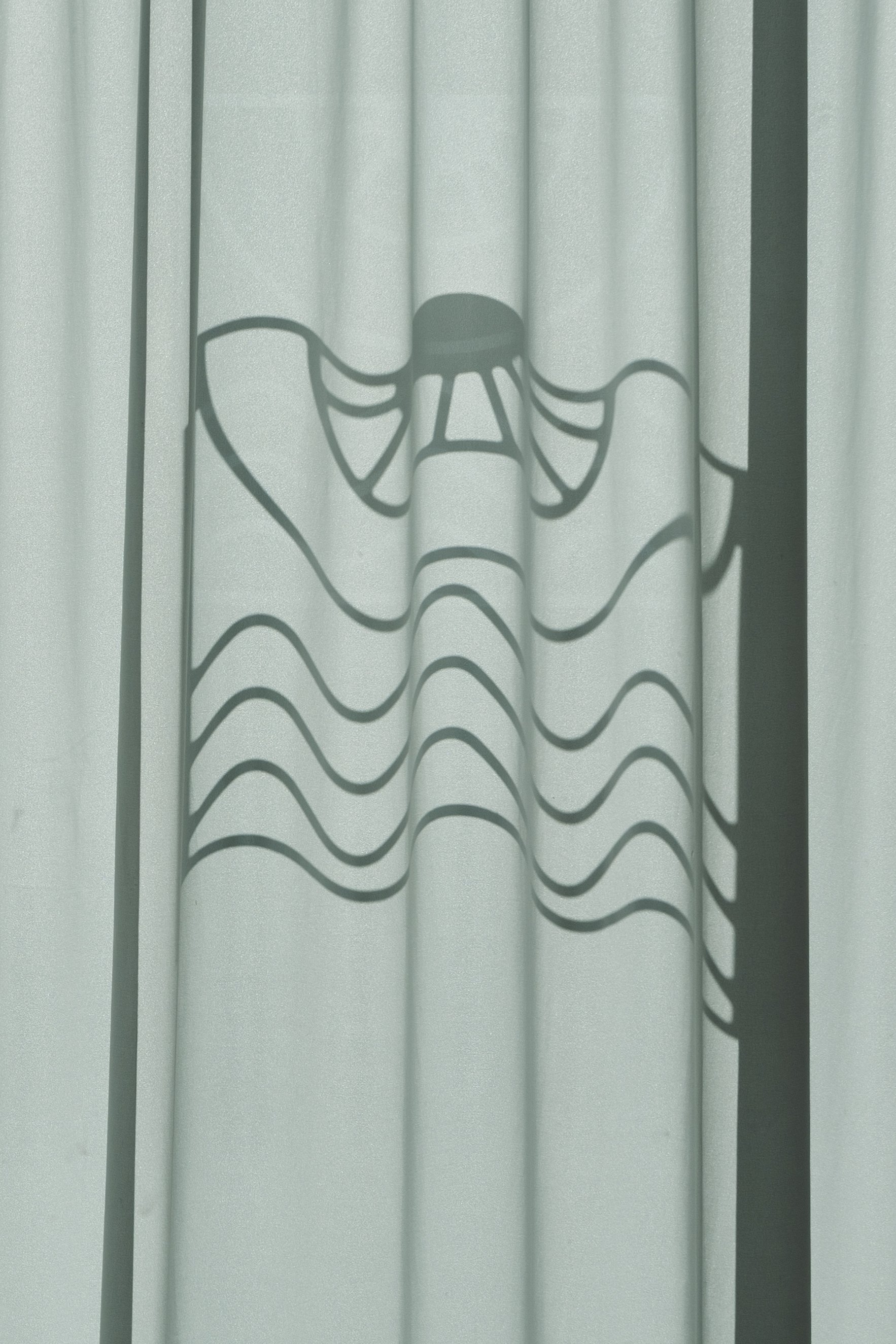 Shadow of a Stormtrooper helmet from Star Wars cast on a curtain.