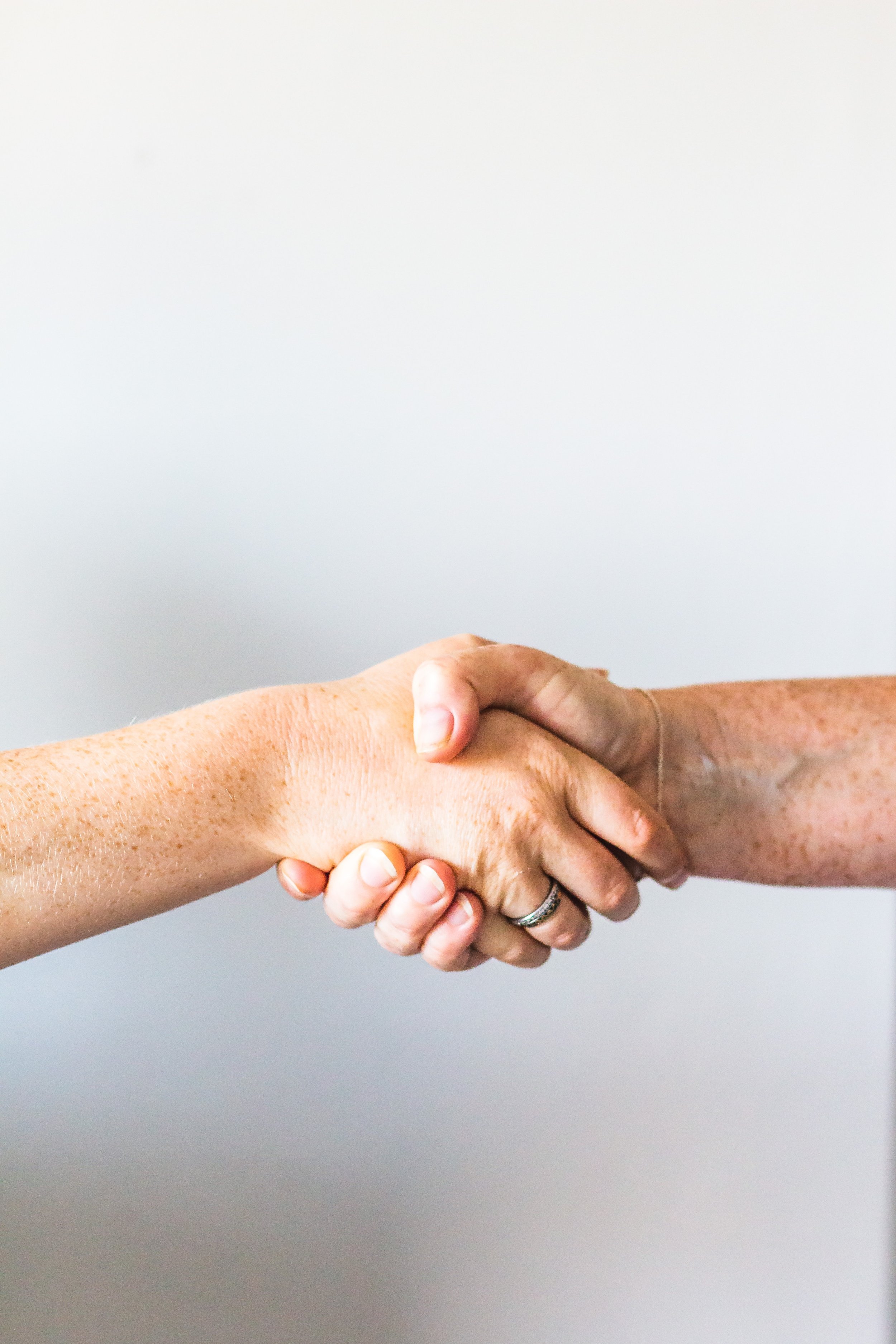 Two people shaking hands against a plain white background.