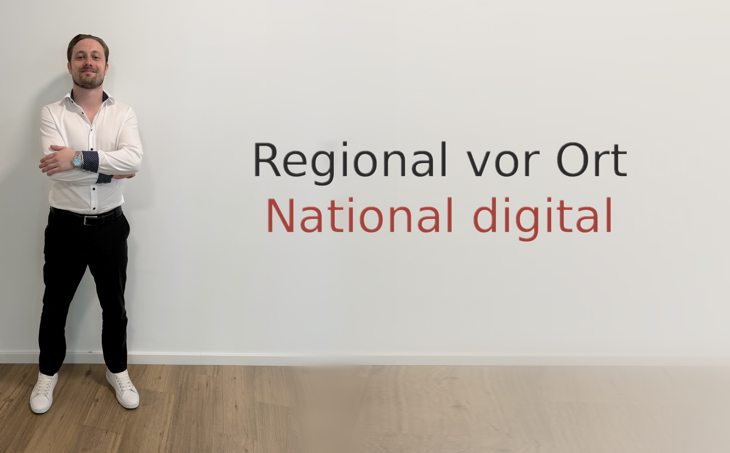 Ein Mann steht vor einer weißen Wand mit einem Text, der lautet: 'Regional vor Ort, National digital'.