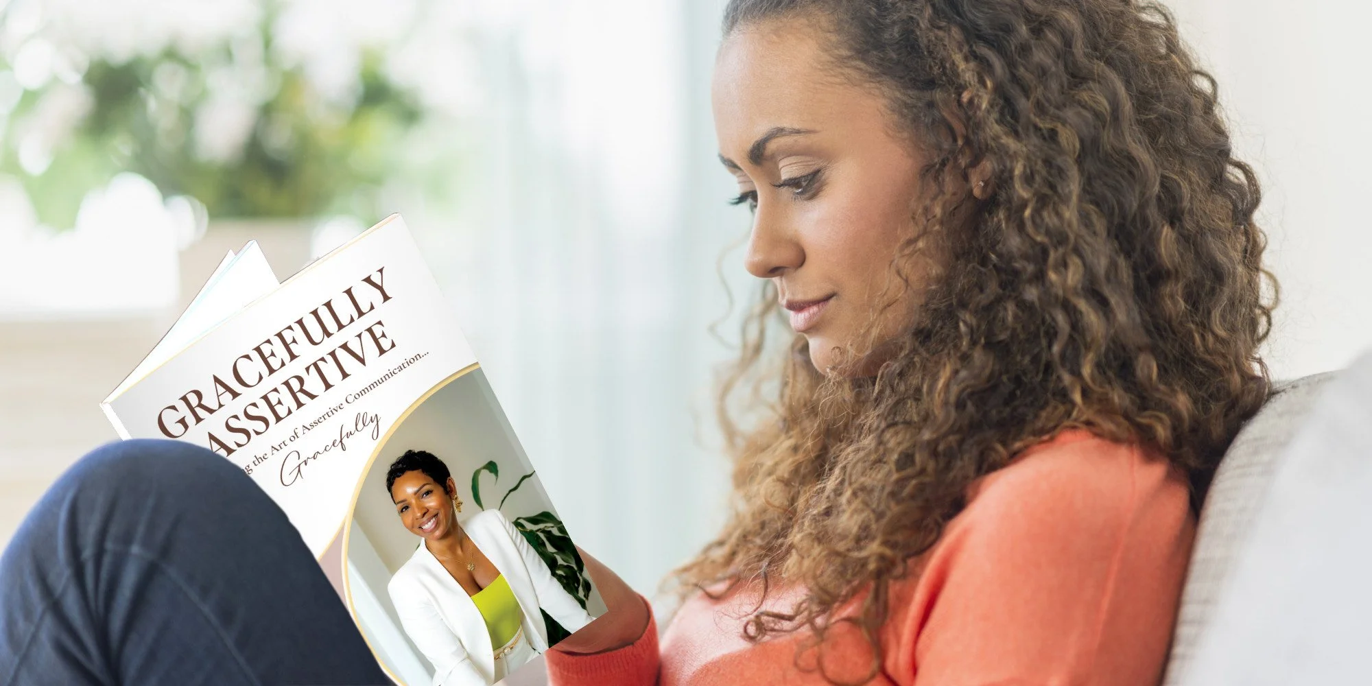 A woman with curly hair is reading a book titled 'Gracefully Assertive' while sitting on a sofa.