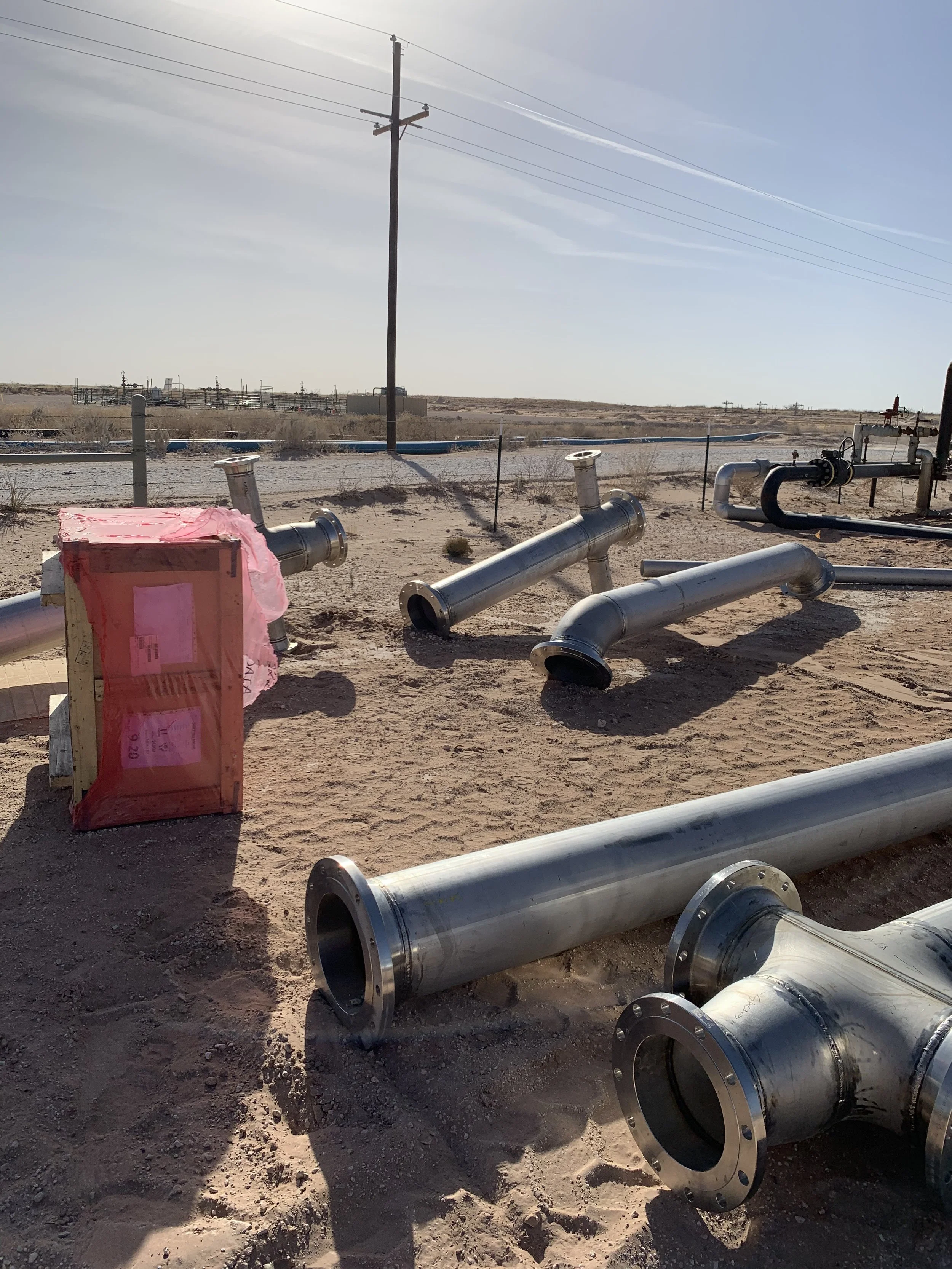 Construction site in a desert landscape with stainless steel pipe fabrication laying on the sand | John 6:9 Welding Company LLC | Sedalia, MO