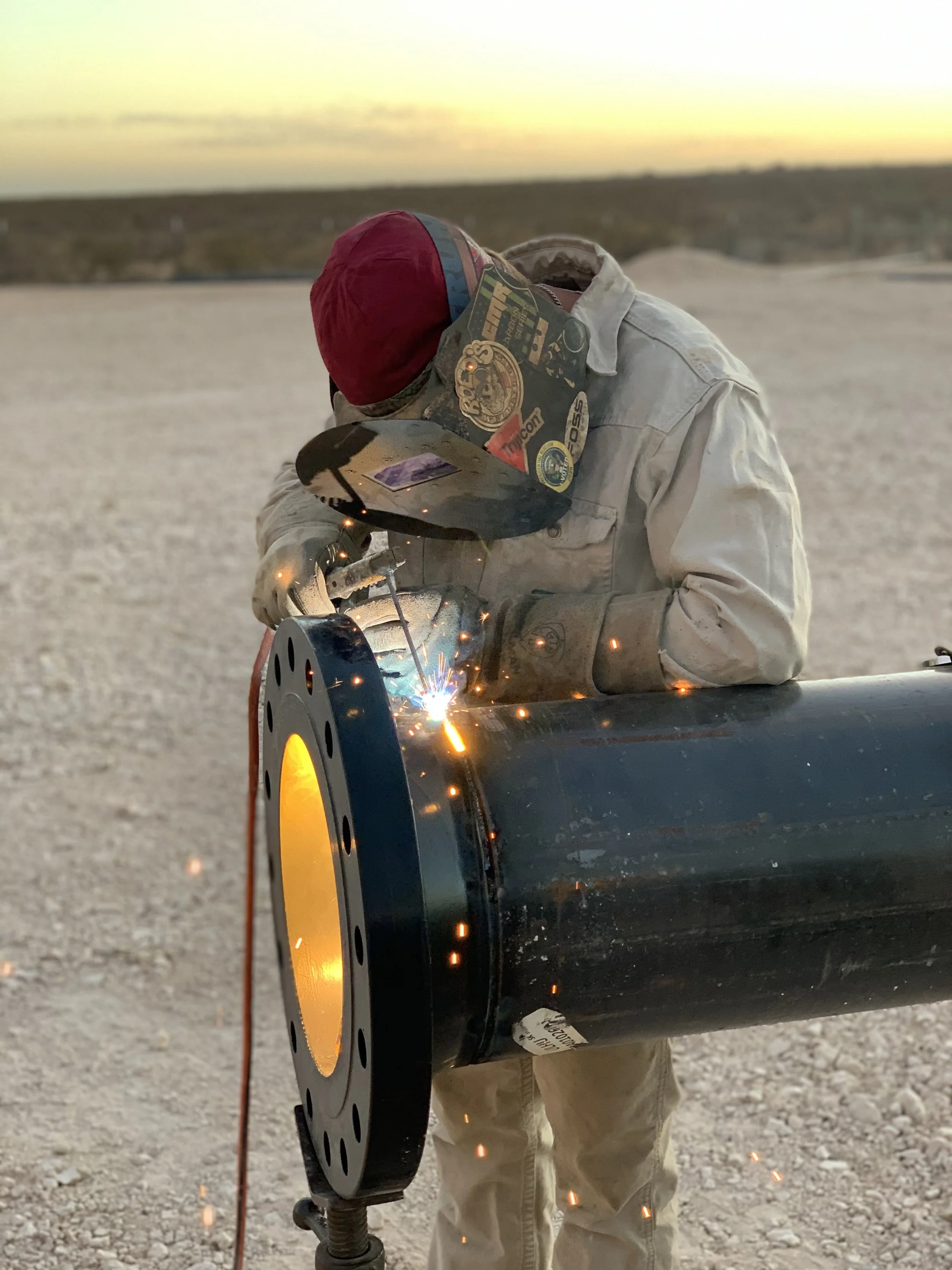 A person welding a metal pipe outdoors during sunset | John 6:9 Welding Company LLC | Sedalia, MO
