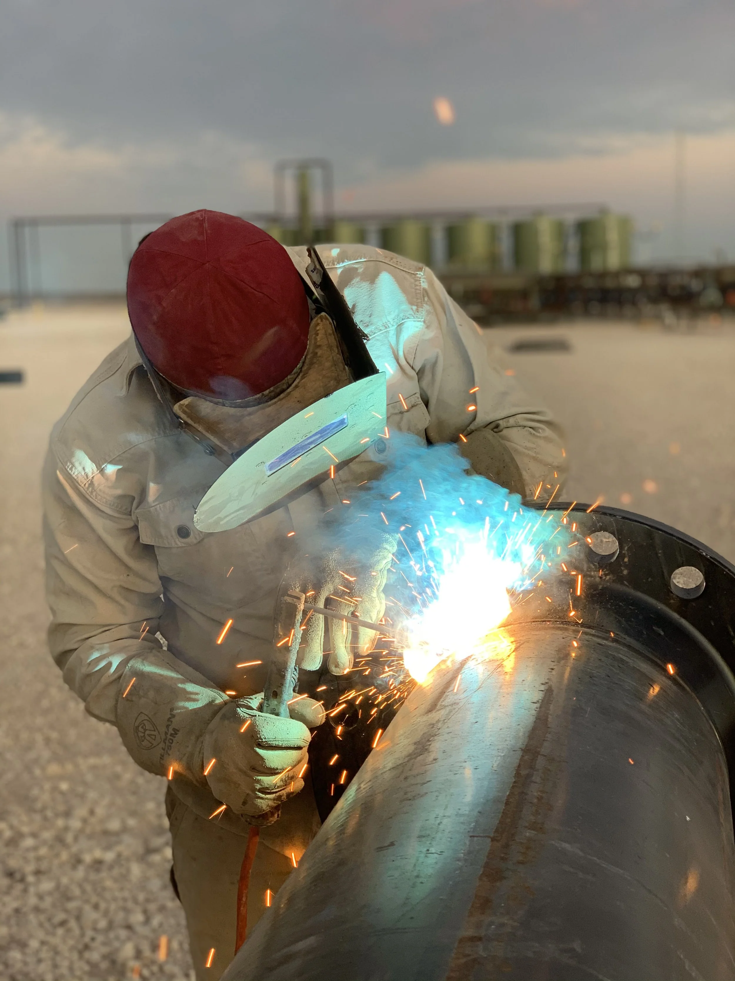 A person welding a metal pipe outdoors during sunset | John 6:9 Welding Company LLC | Sedalia, MO