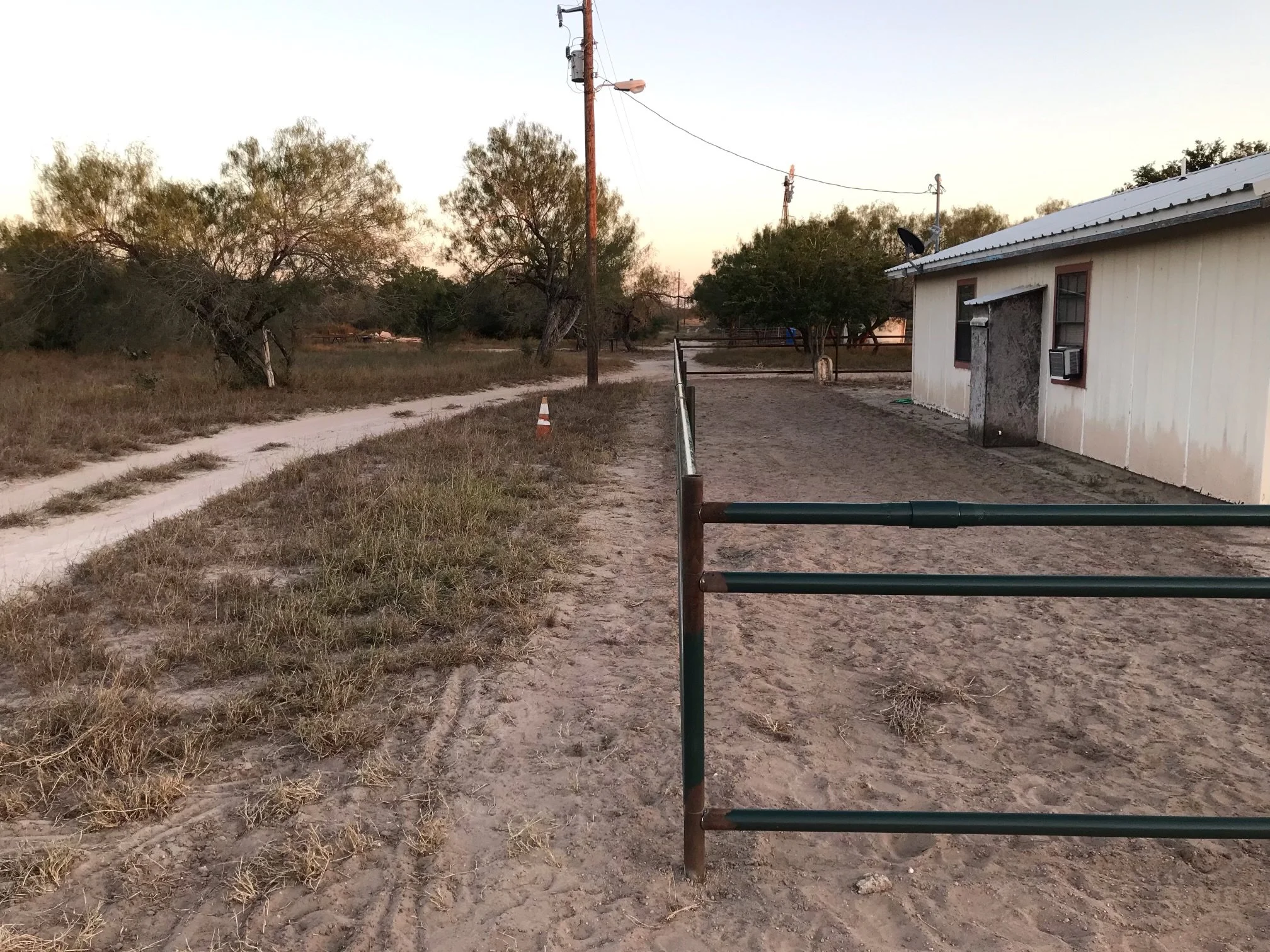A rural scene during sunset with a dirt path, with a custom fabricated pipe fence | John 6:9 Welding Company LLC | Sedalia, MO