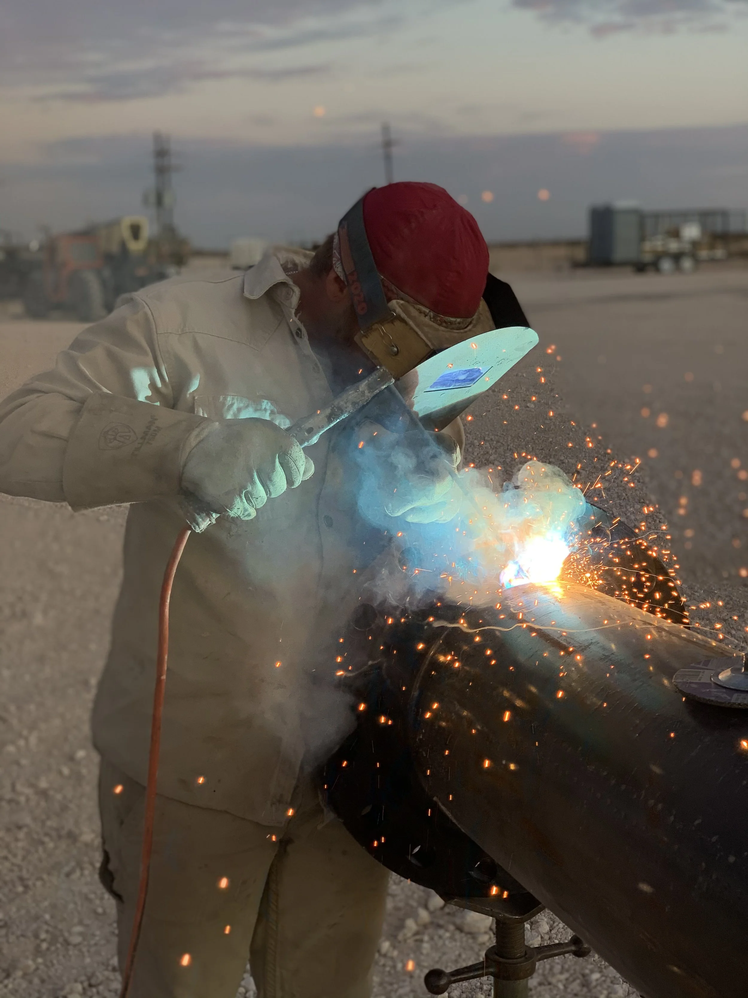 A person welding a metal pipe outdoors during sunset | John 6:9 Welding Company LLC | Sedalia, MO