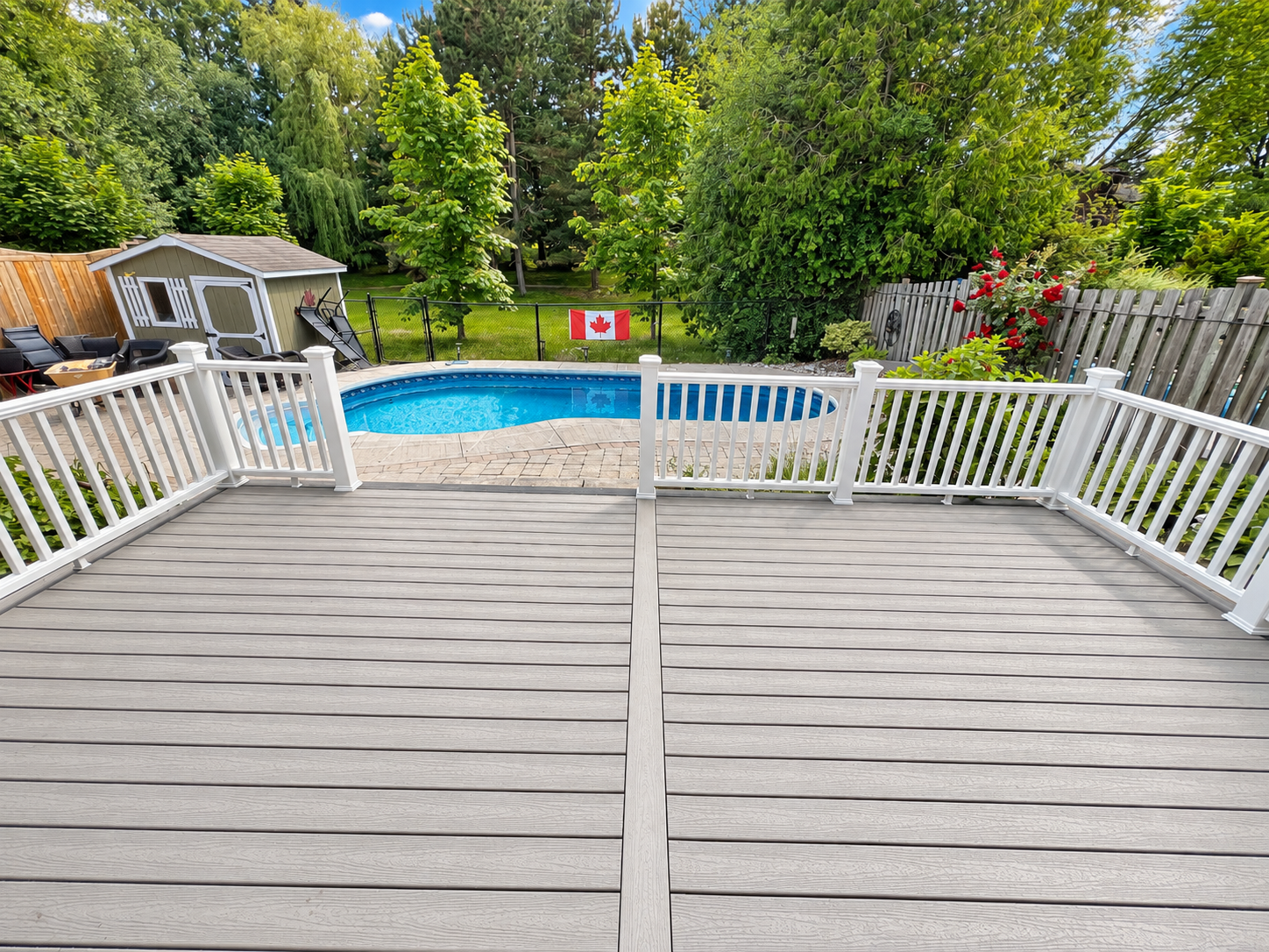 Backyard view from a deck showing an above-ground swimming pool, a small shed, outdoor chairs, and lush green trees with a Canadian flag on the fence.