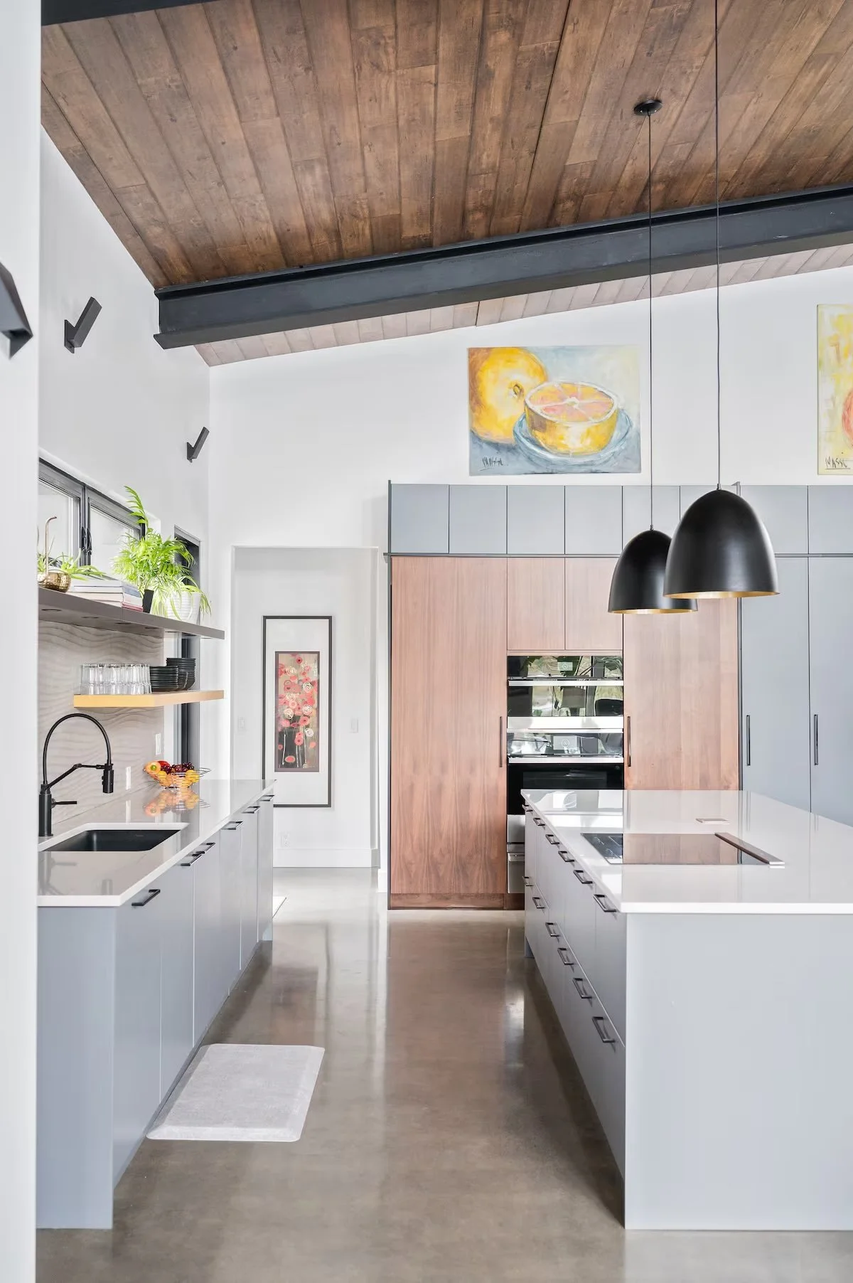 Modern kitchen with white cabinetry, wooden accents, pendant lighting, and art on the walls.
