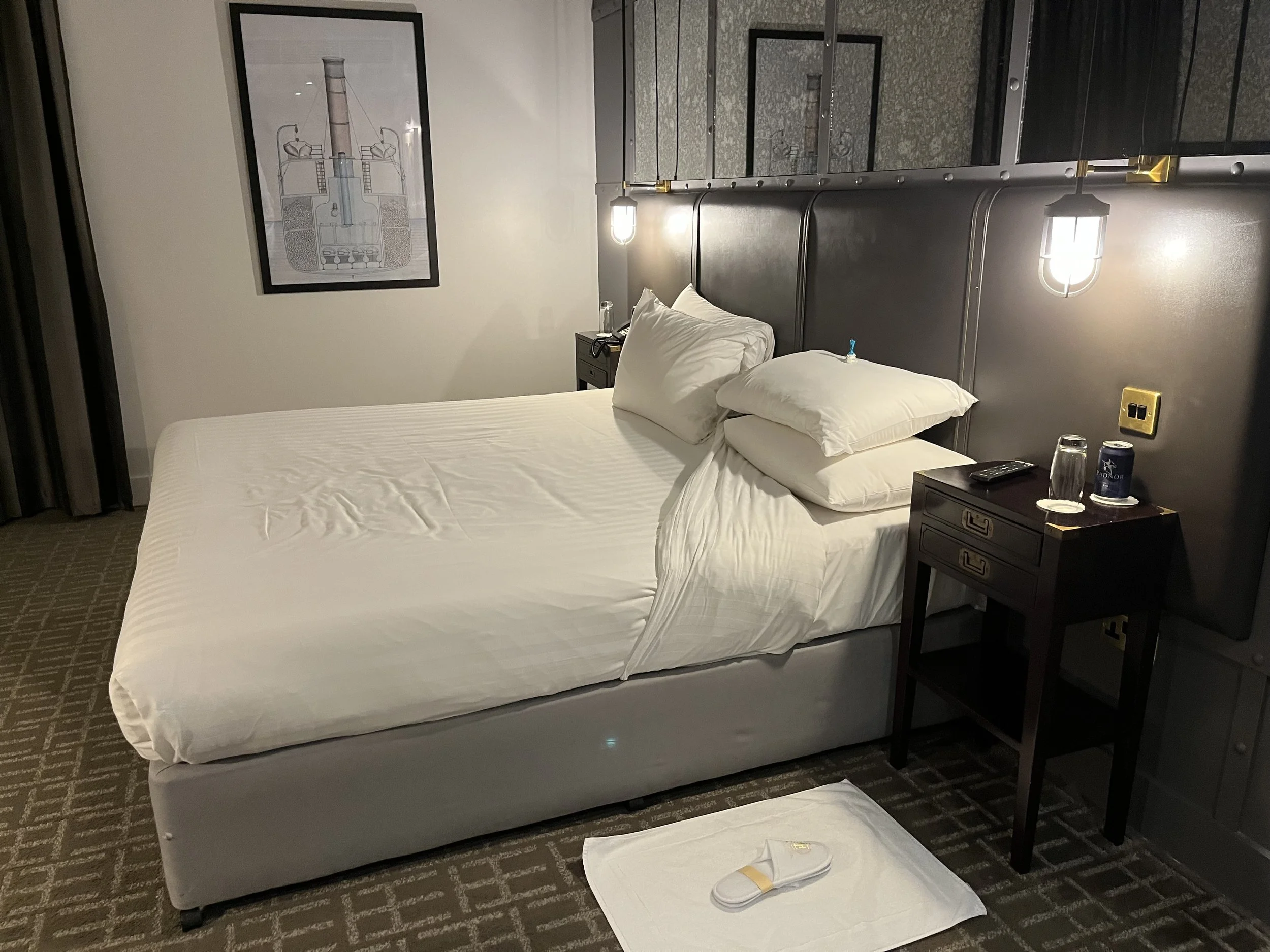 Chambre supérieure spacieuse avec un lit king size confortable, quatre oreillers moelleux, une table de chevet dans la style bateau de croisière transatlantique.