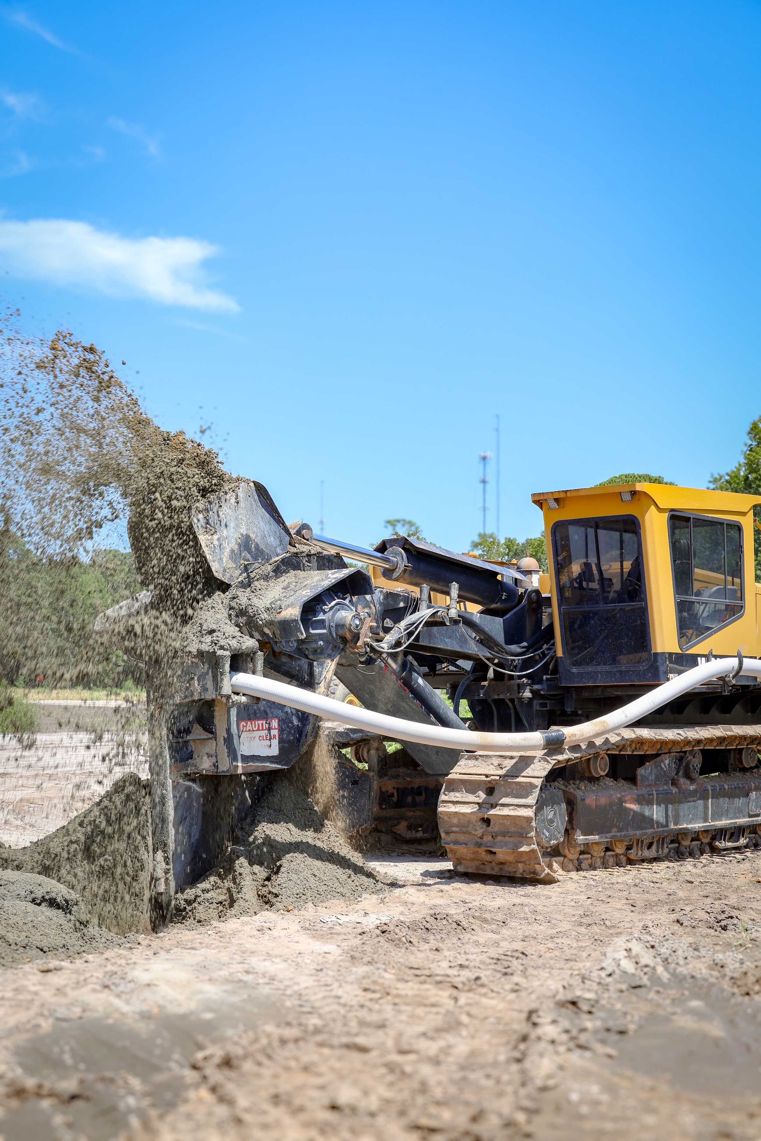 A bulldozer spreading soil or gravel at a construction site under a blue sky. (Deepwater Dewatering machine -Hollywood, SC)