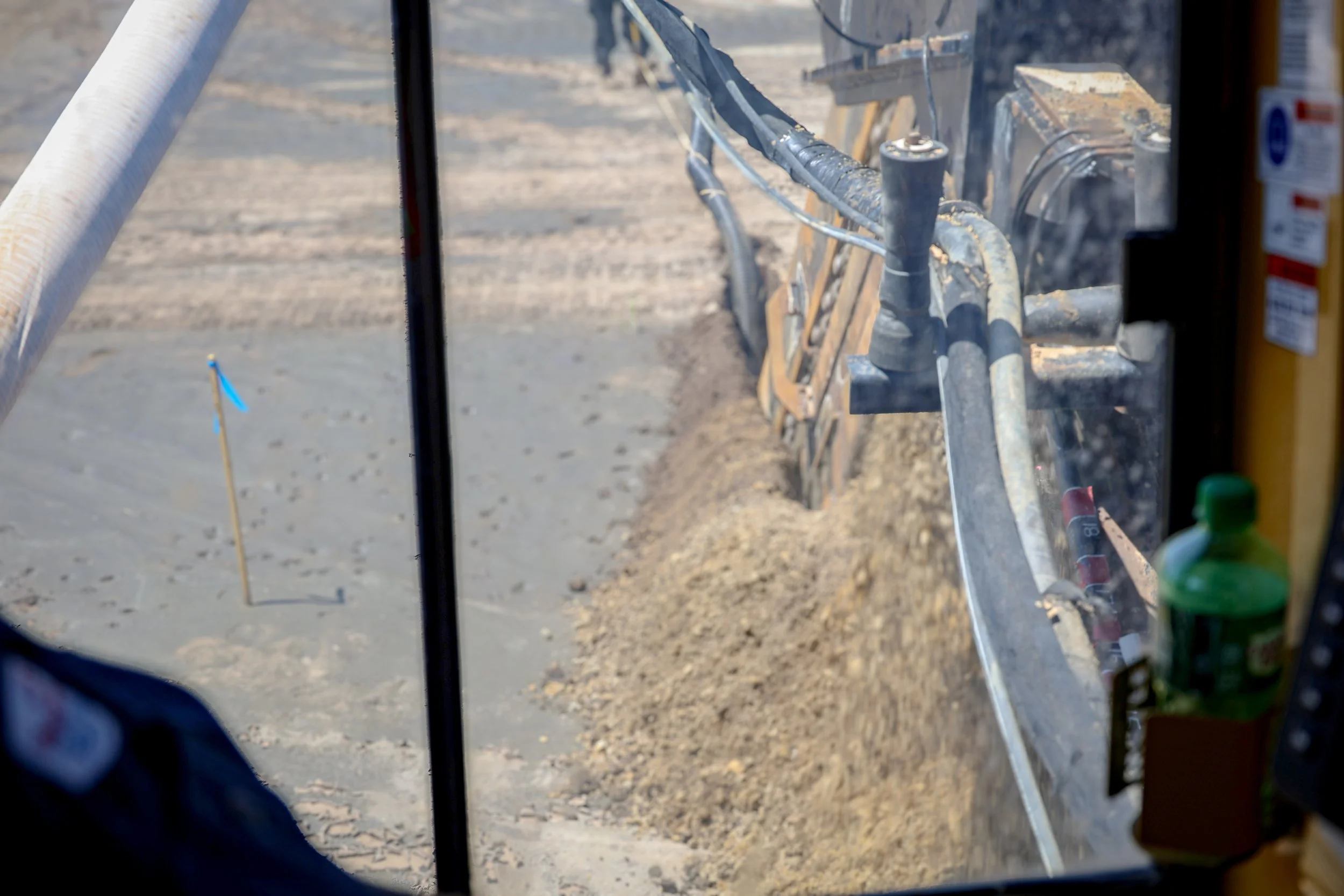 View from inside construction vehicle cab showing hydraulic equipment and dirt ground at construction site (Deepwater Dewatering machine -Hollywood, SC)