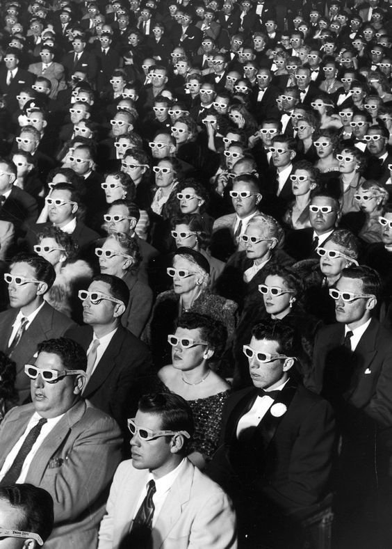 Black-and-white photograph of a cinema audience wearing 3D glasses.
