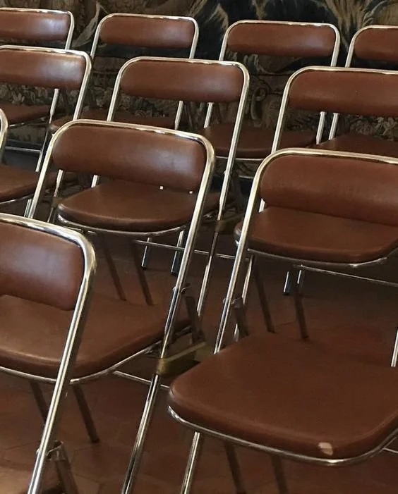 Rows of vintage brown leather folding chairs.