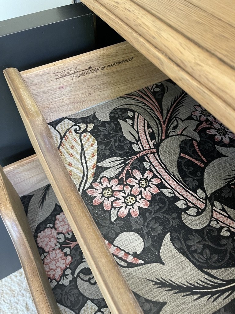Open wooden drawer with floral-patterned fabric lining.
