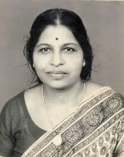 A black and white portrait of a woman wearing traditional Indian attire with a sari, jewelry, and a bindi on her forehead.