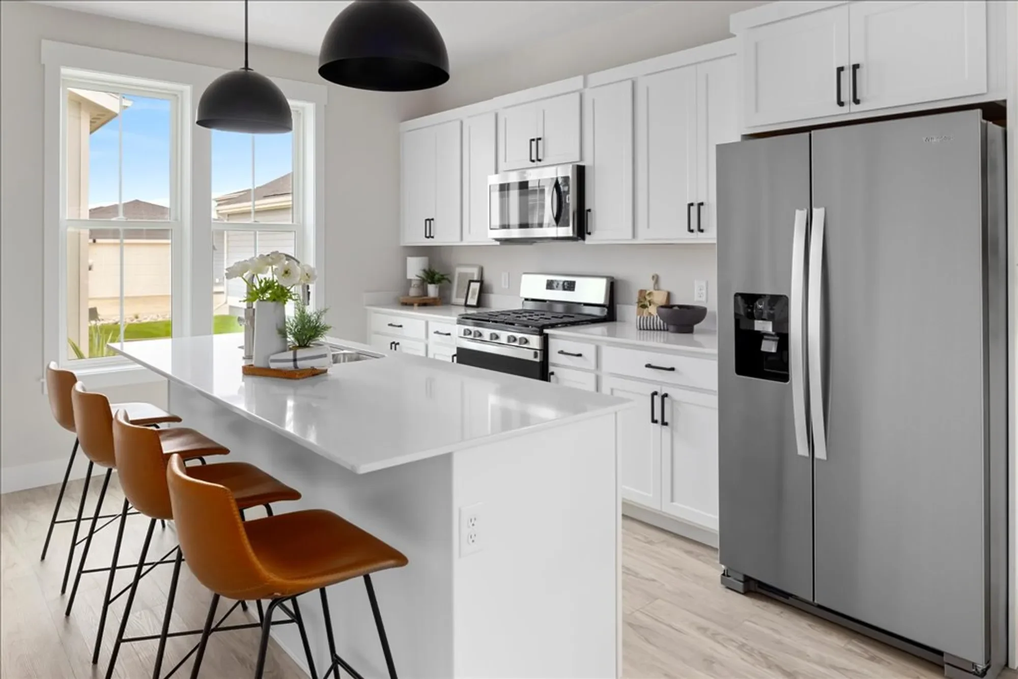 Interior view of a brand new 44 West townhome kitchen featuring custom Burl stained birch cabinets, durable TAS Ambiance Orion LVP flooring, and premium Carrara quartz countertops.