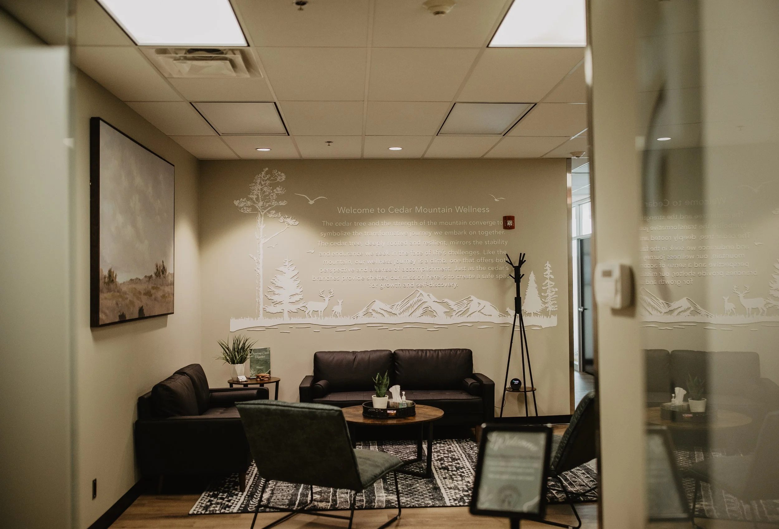 Interior of a wellness center with sitting area, wall mural featuring trees and mountains, and welcoming text about cedar trees and mountain strength