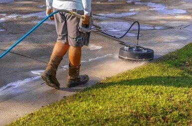 Person using a string trimmer to edge a concrete sidewalk with a grassy area nearby.