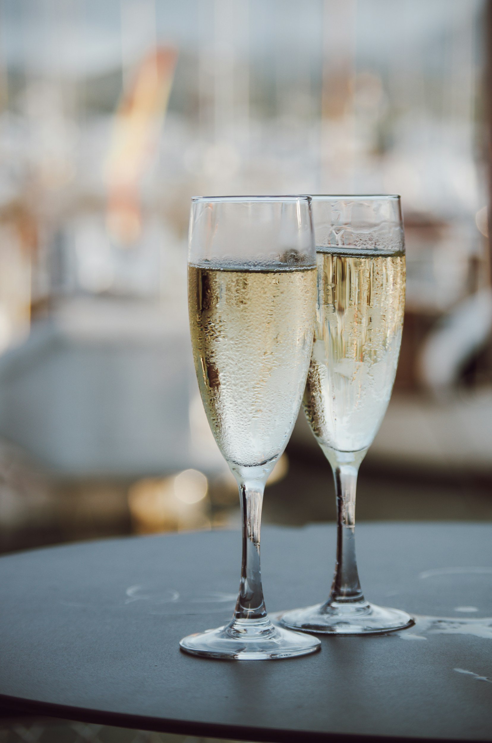 Two champagne glasses filled with sparkling wine on a table, with a blurred background.
