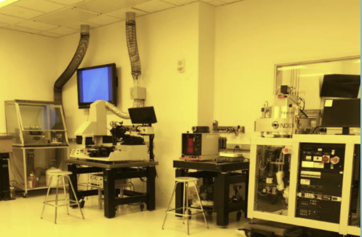 Laboratory with scientific equipment, computers, and workbenches in a well-lit room.