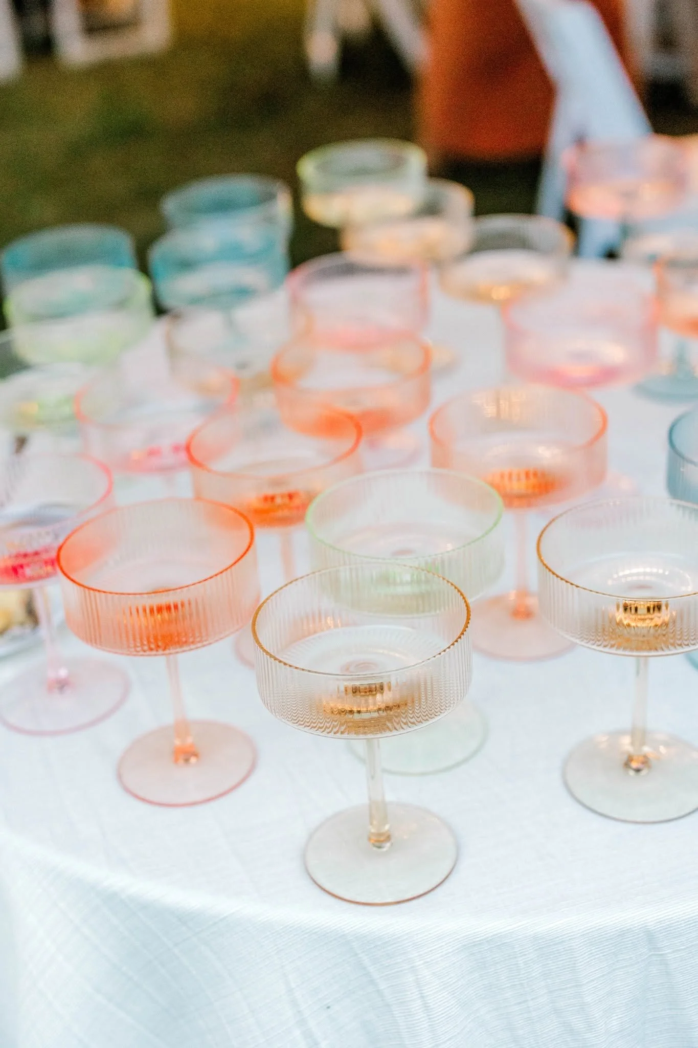 Colorful plastic or acrylic cupcake wrappers displayed on a white table, with a blurred person in a red shirt in the background.