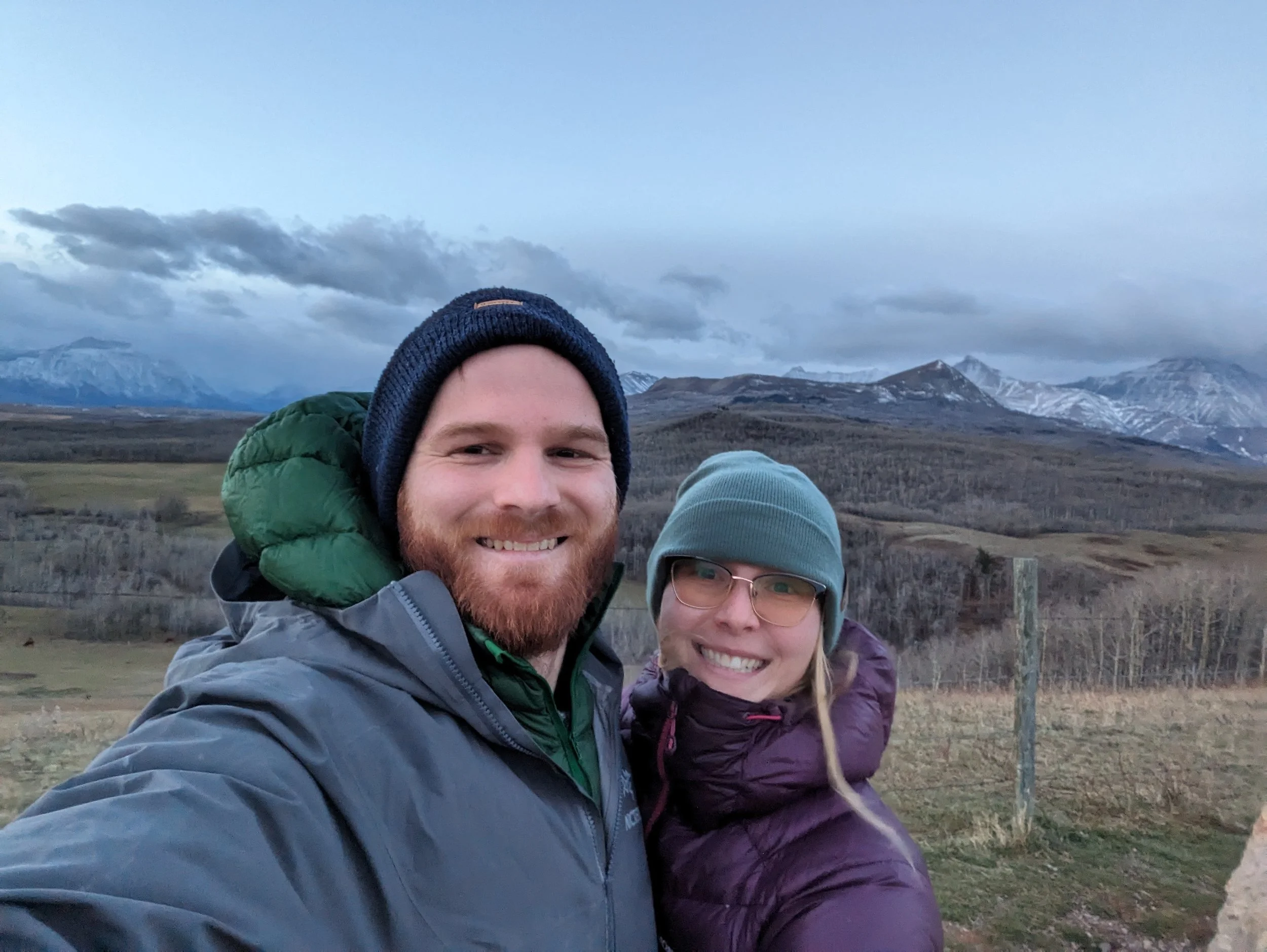 A smiling man and a woman, standing outdoors with mountains and cloudy sky in the background.  The Richard Family own Gower Construction Ltd., a family business located in Invermere, British Columbia, serving BC, and Alberta.