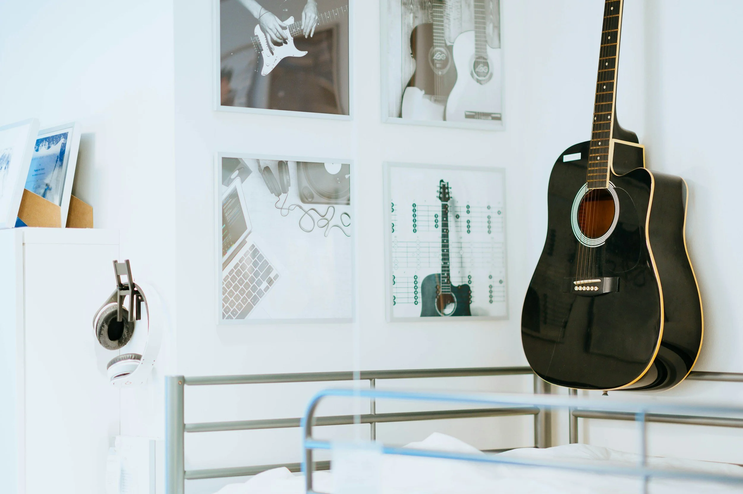 Display case with musical instruments and accessories, including an electric guitar, acoustic guitars, headphones, and framed pictures on the wall.