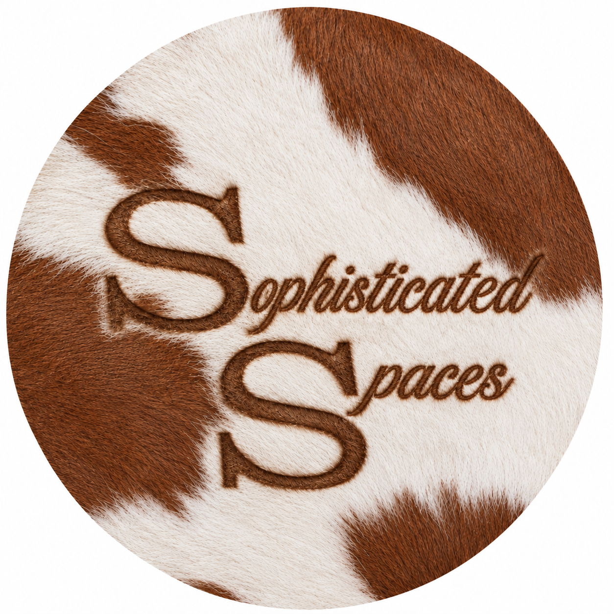 Embroidery on a cowhide with the words "Sophisticated Spaces" stitched in brown thread.