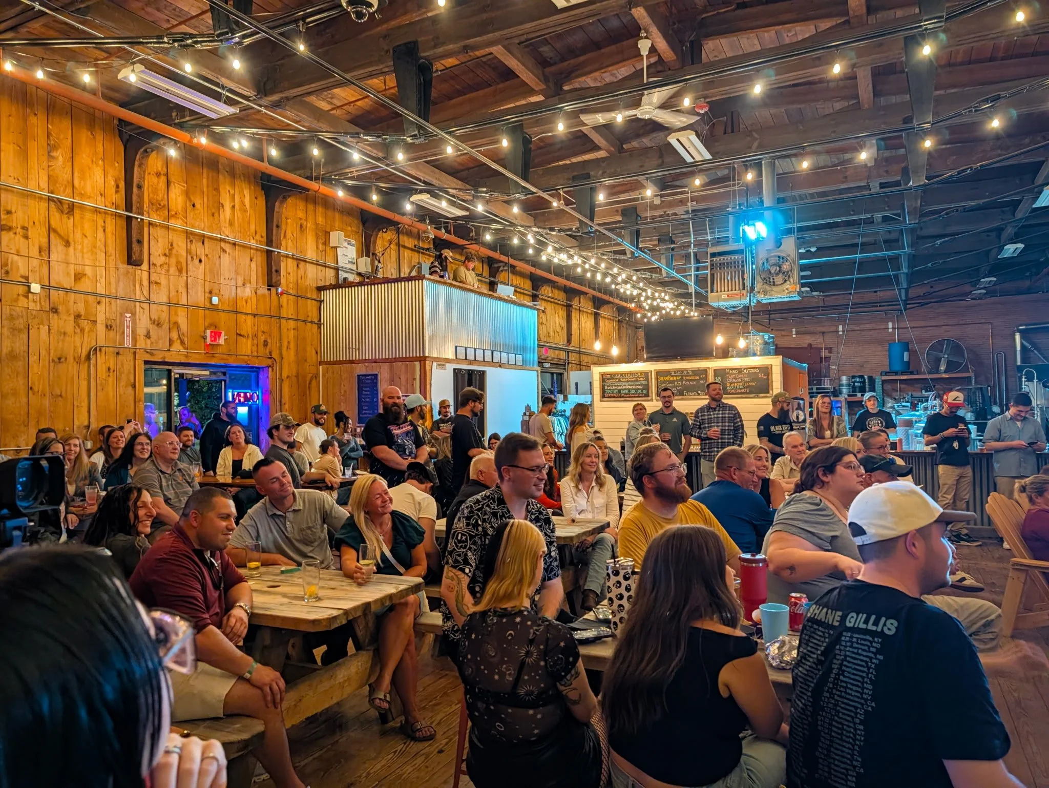 A roast battle in a brewery with a large crowd of attendees enjoying the show