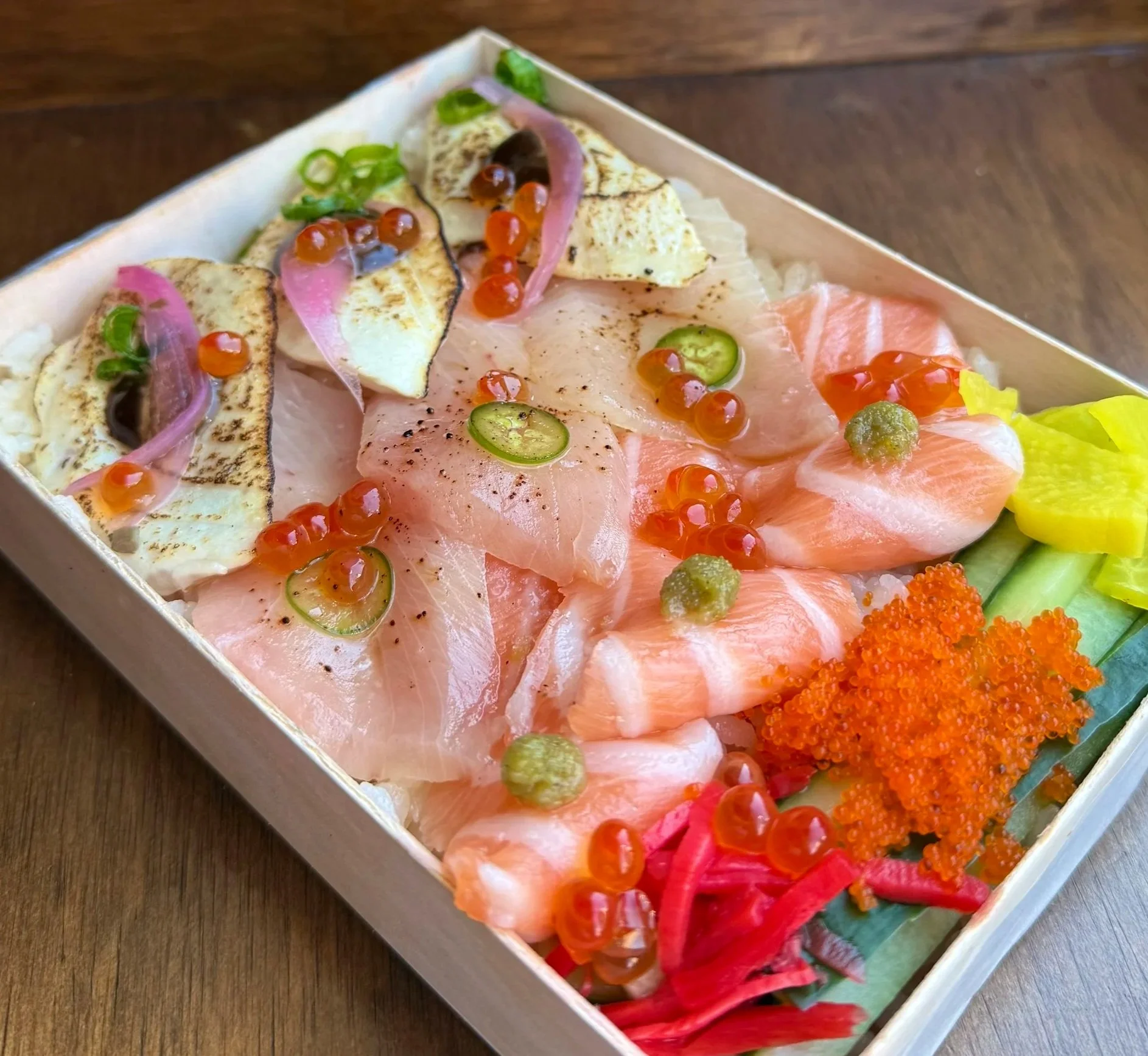 Chirashi box with an assortment of sashimi atop sushi rice.