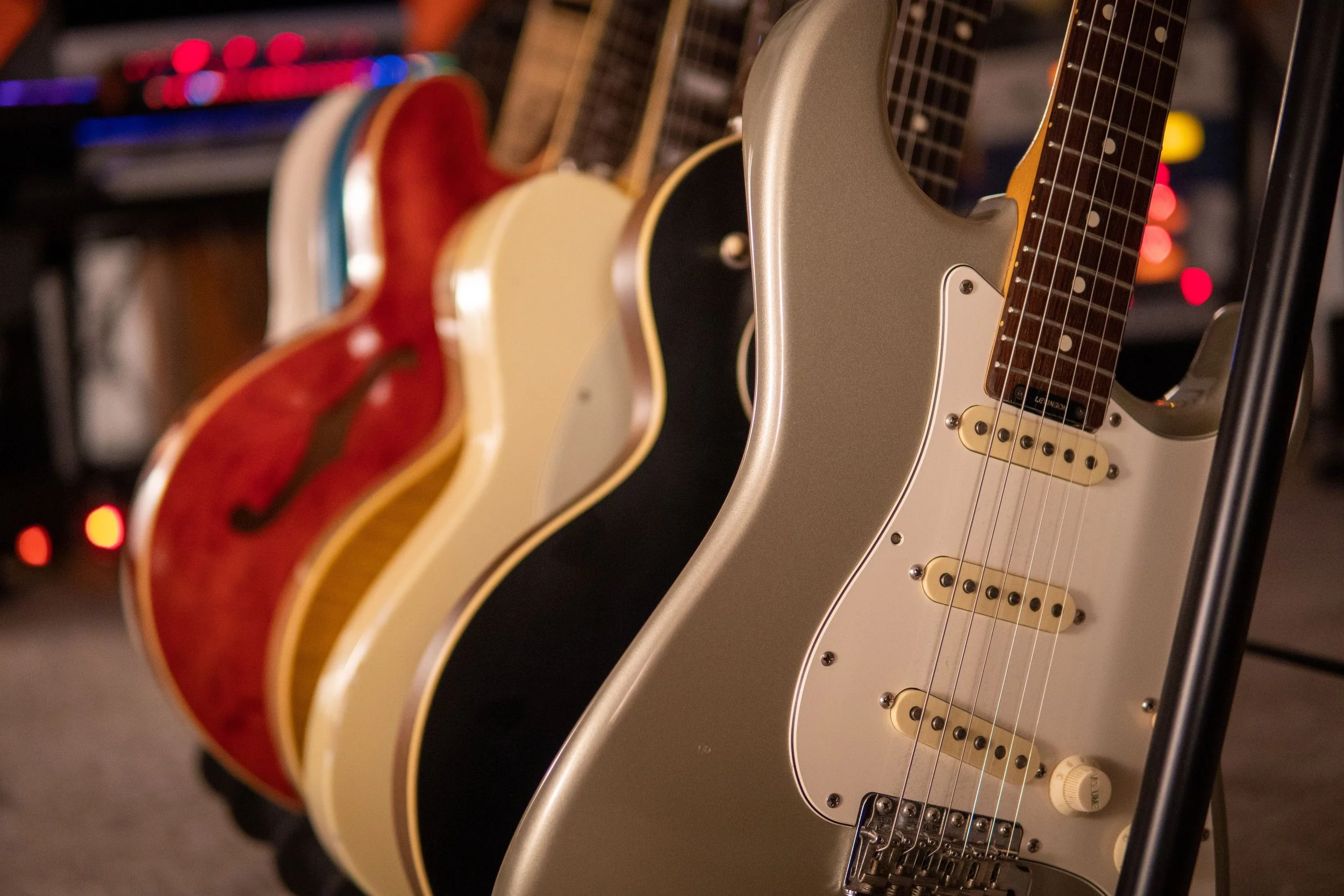 Multiple electric guitars hung vertically on a display rack, featuring different colors and designs.