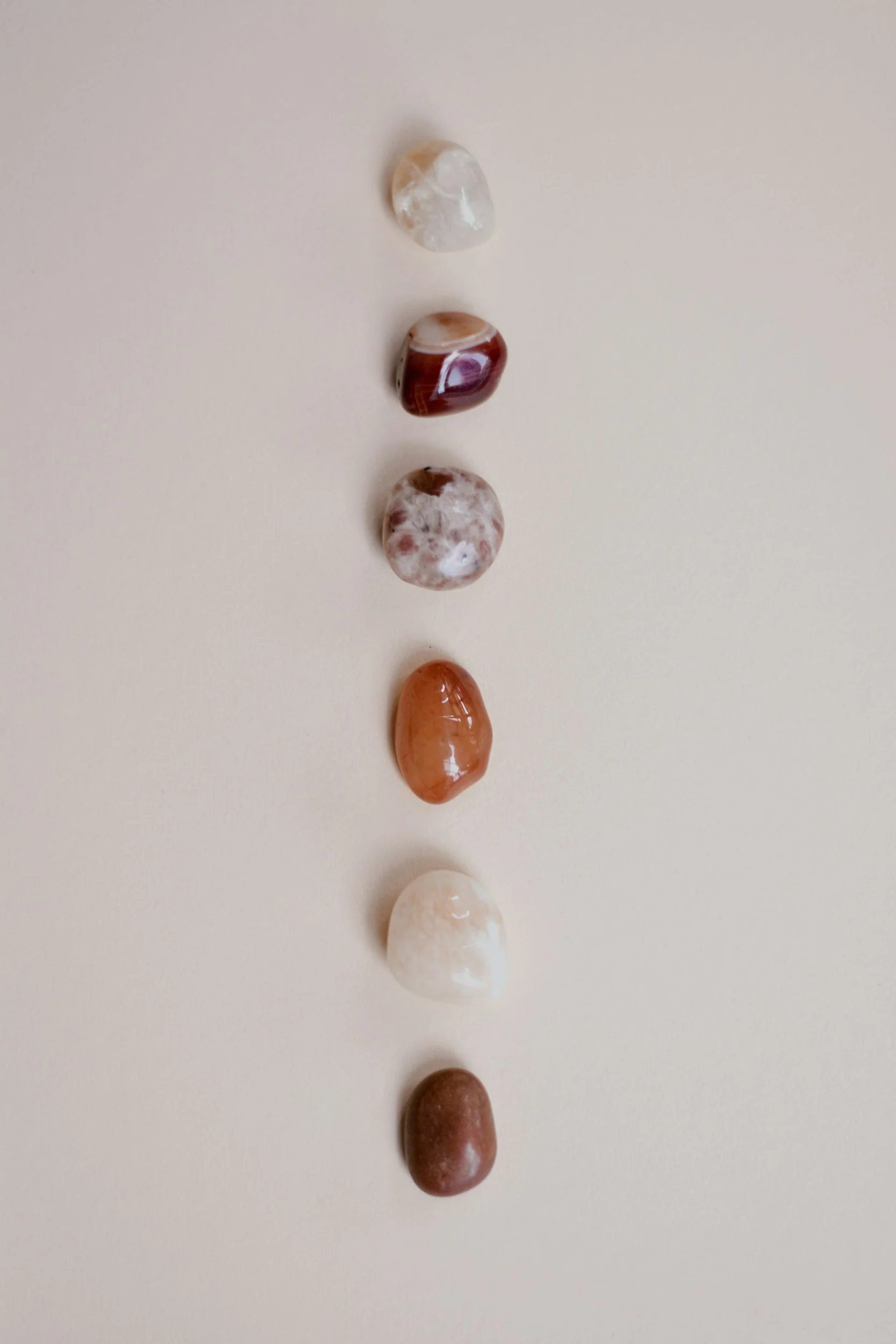 Seven polished semi-precious stones arranged vertically on a light background.