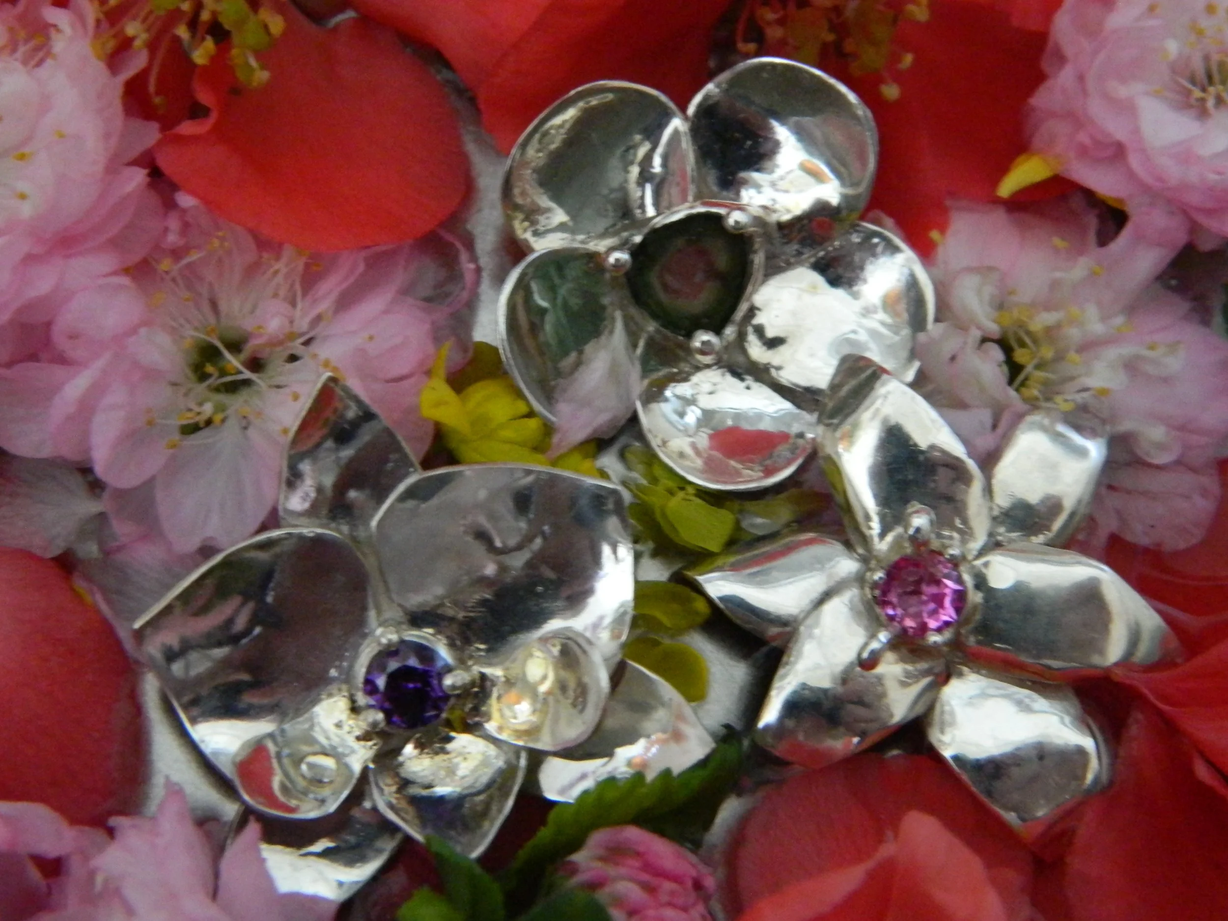 Close-up of a decorative silver flower-shaped item surrounded by pink flowers on a red background.