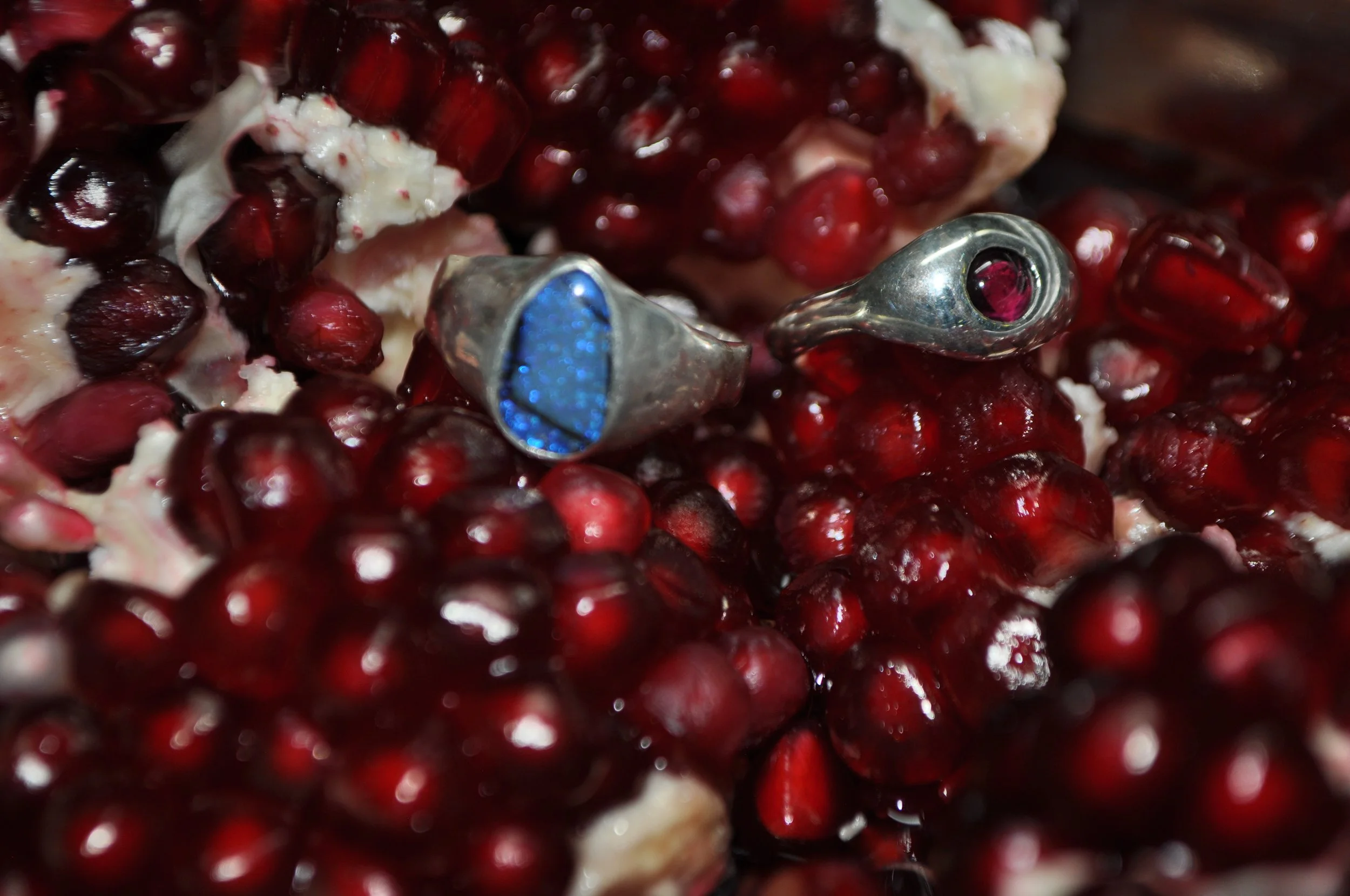 Close-up of pomegranate seeds with two metallic earphones resting among the seeds.