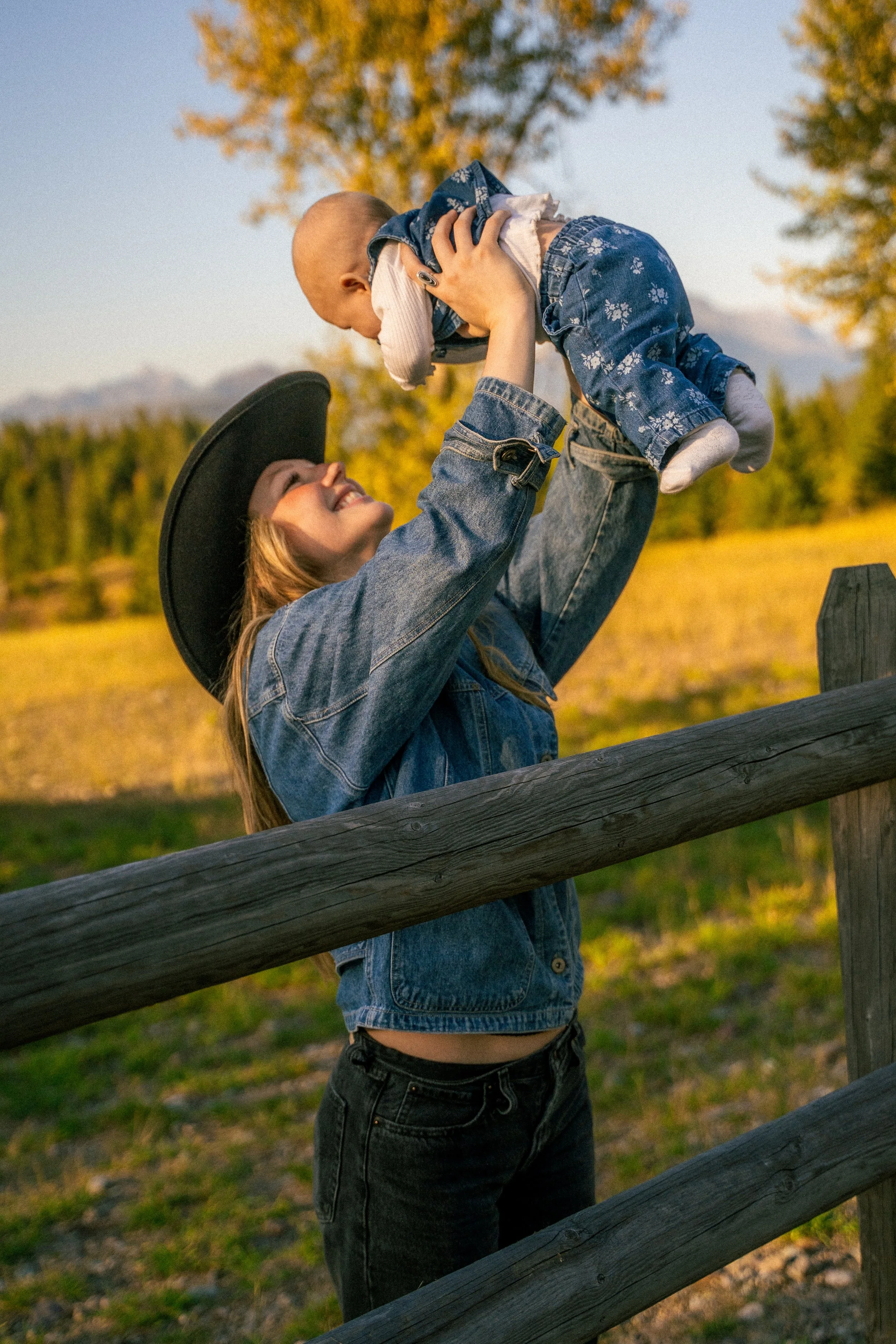 Smiling woman holding a baby in autumn foliage outdoors