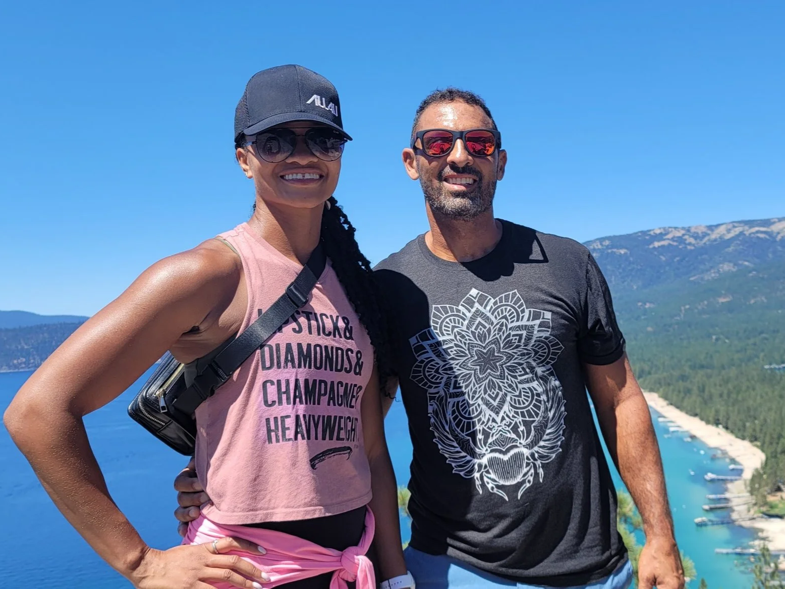 Bassem Elsayeh and his wife on a mountain trail overlooking Lake Tahoe, forested slopes and a marina below